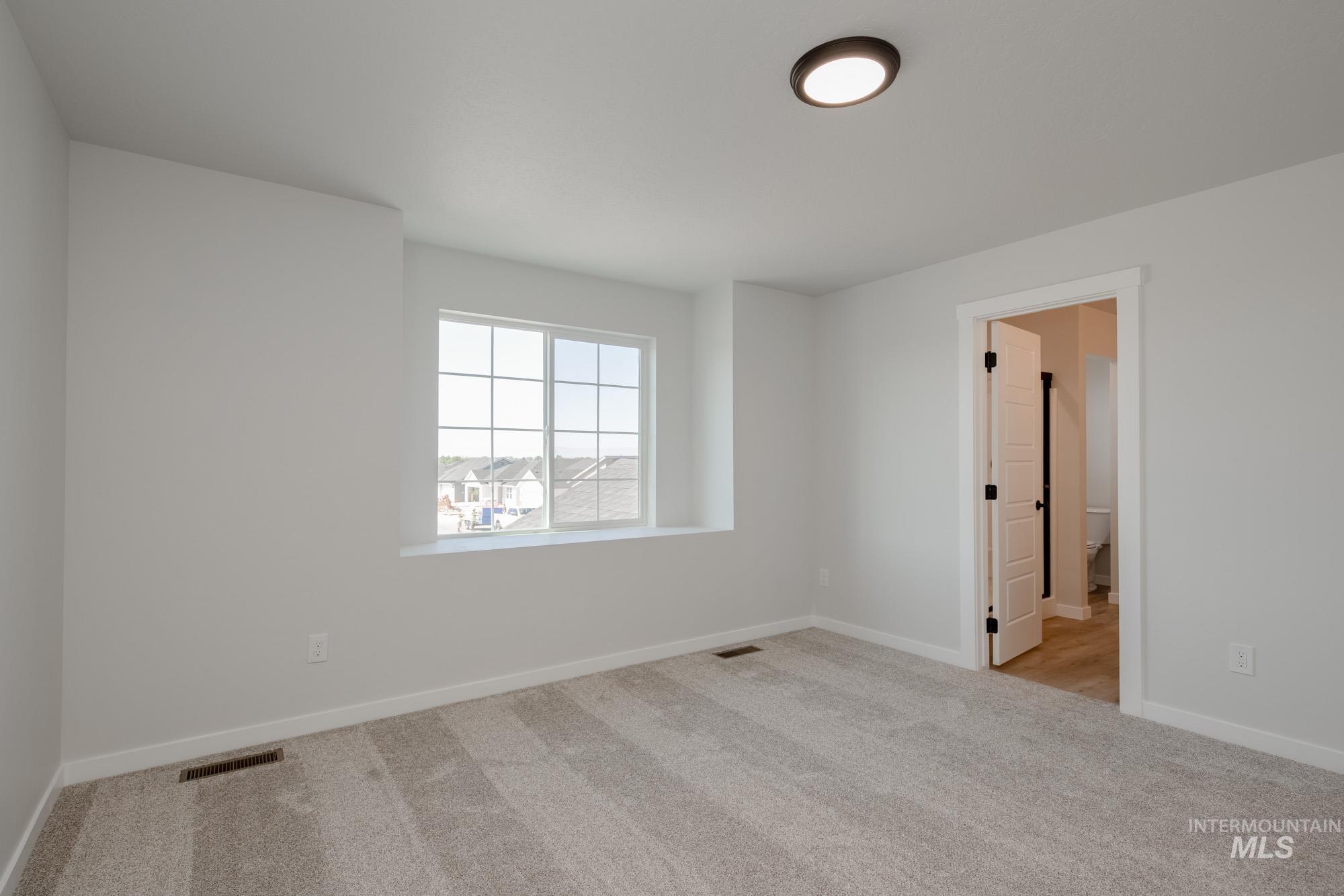 Empty room with light colored carpet and baseboards