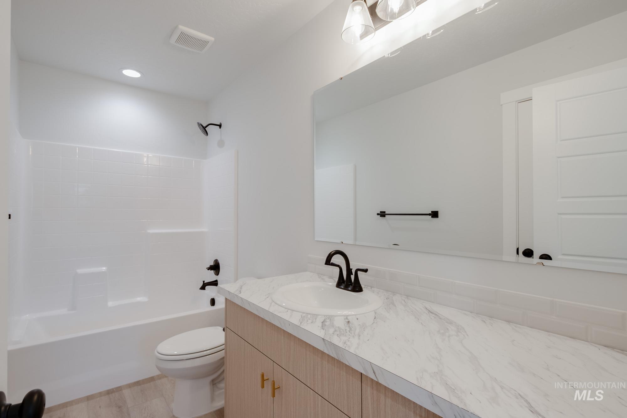 Full bath with vanity, shower / bath combination, and light wood finished floors