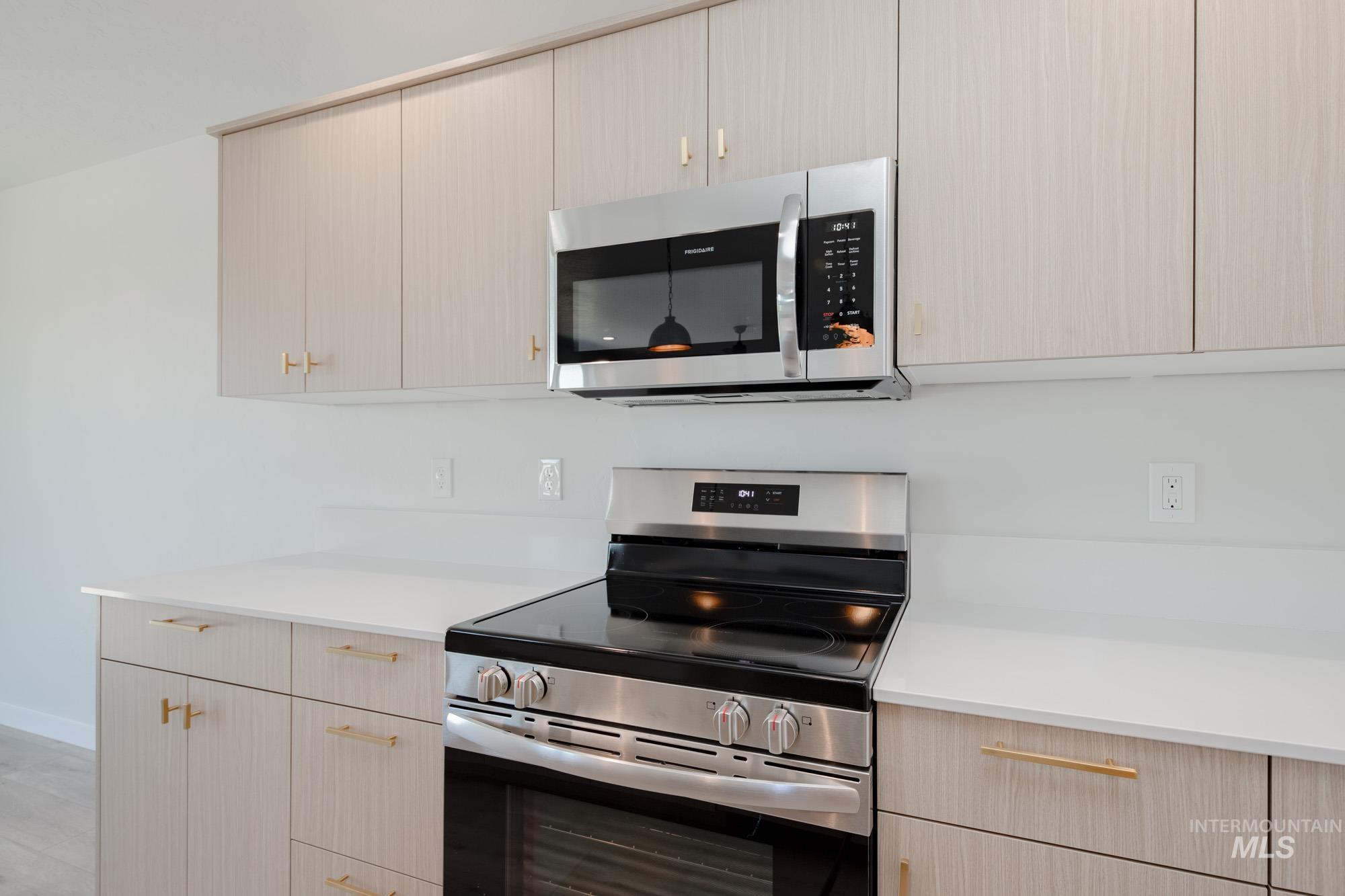 Kitchen with appliances with stainless steel finishes, light brown cabinets, and modern cabinets