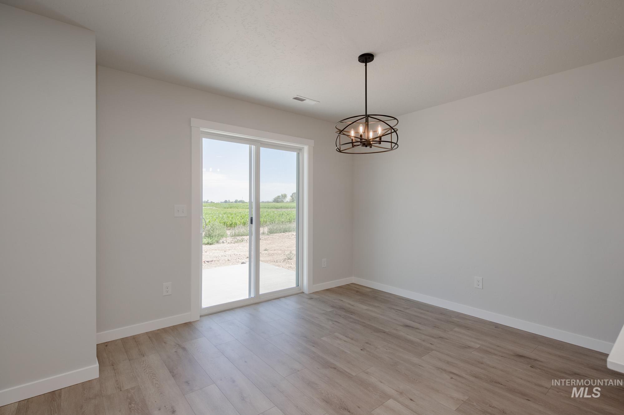 Empty room featuring a chandelier and light wood-style floors