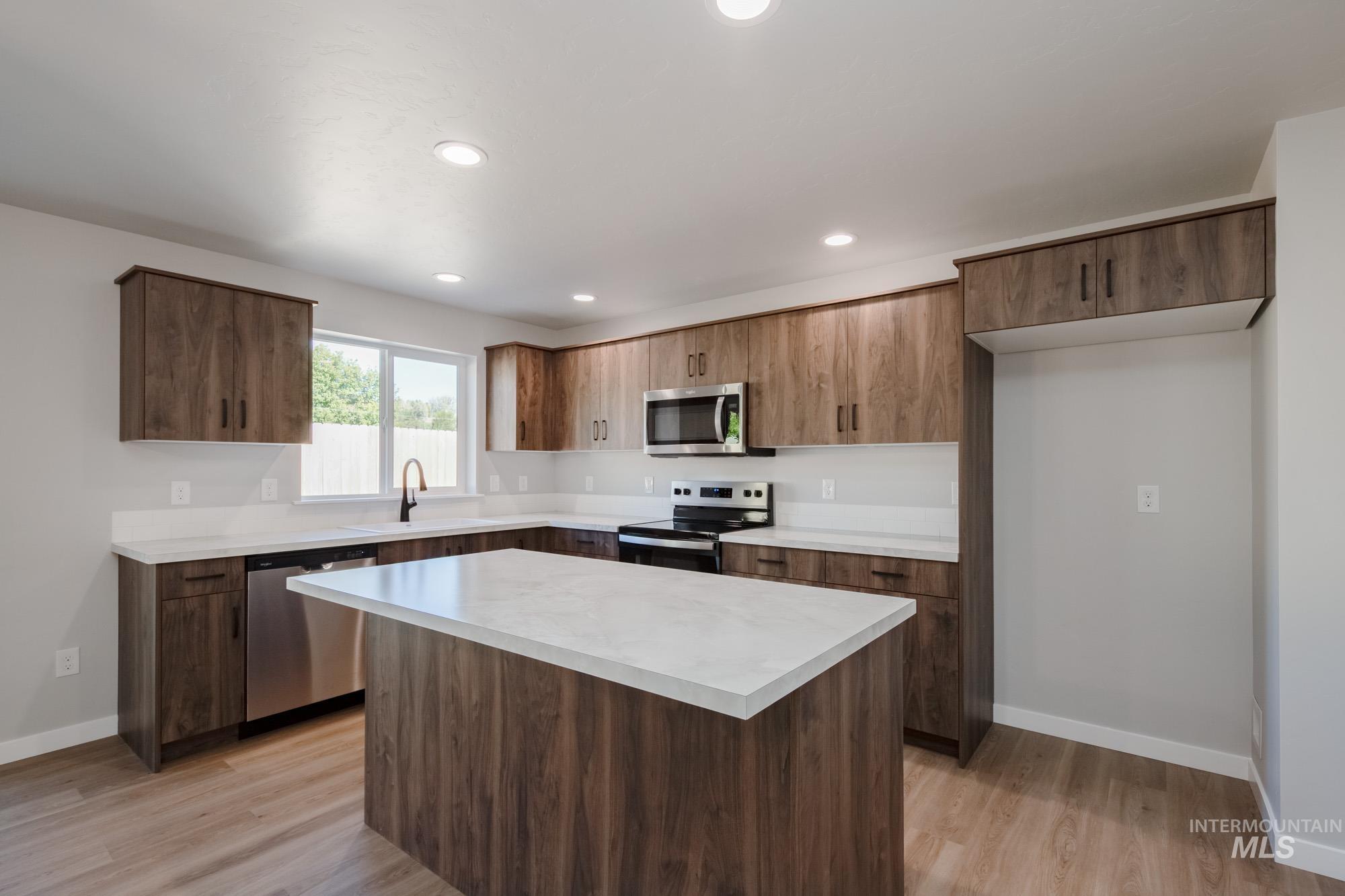 Kitchen with light countertops, a kitchen island, stainless steel appliances, recessed lighting, and light wood-style flooring