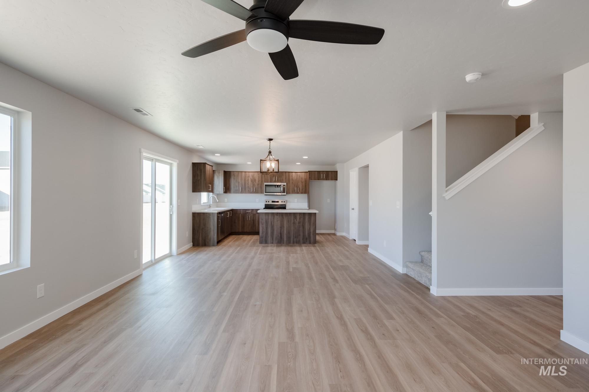 Unfurnished living room with recessed lighting, ceiling fan, light wood-style floors, and stairway