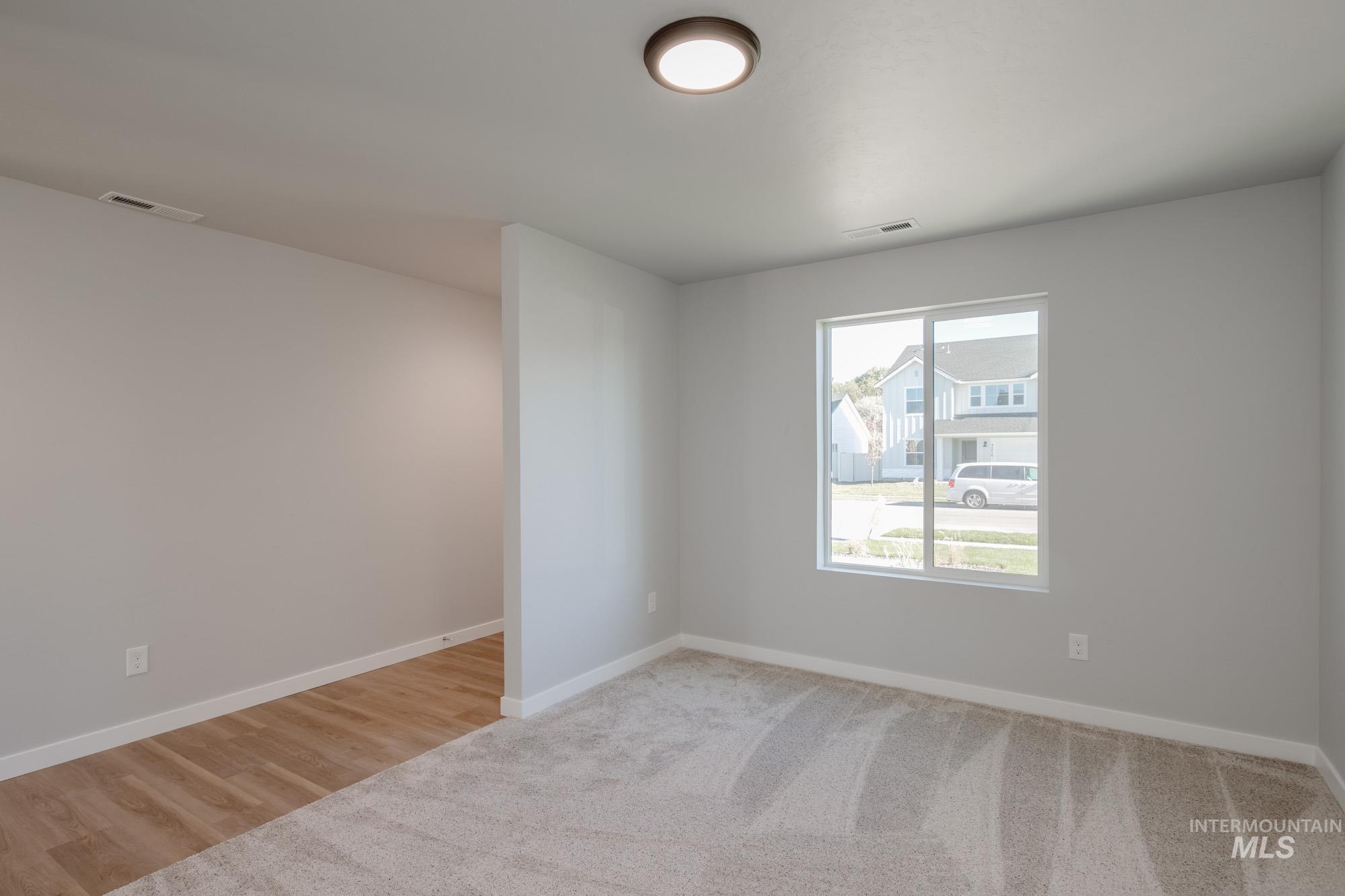Unfurnished room with light colored carpet and light wood-type flooring