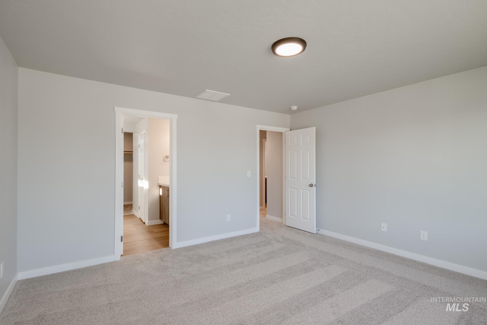 Unfurnished bedroom featuring light colored carpet and ensuite bath