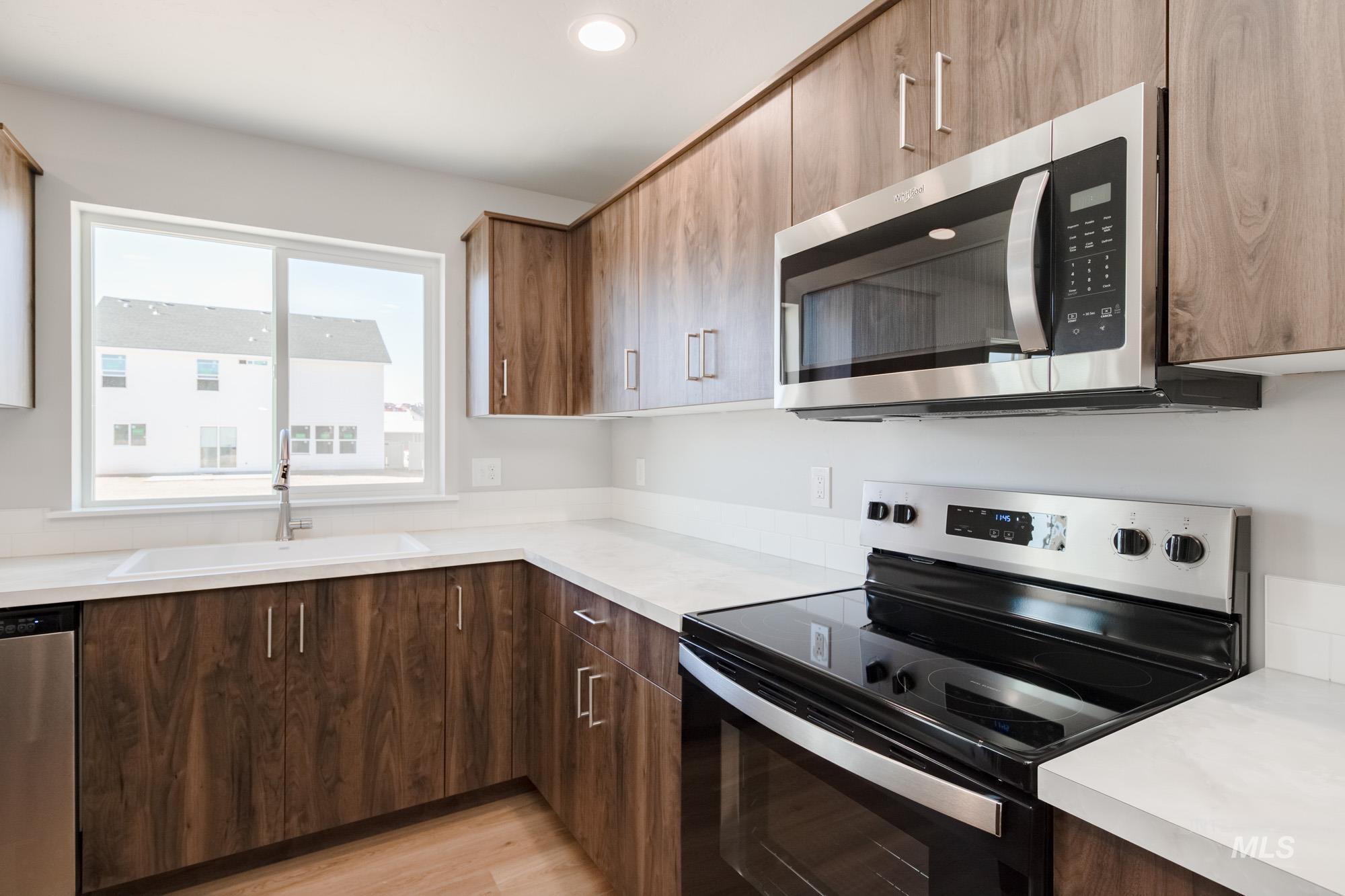 Kitchen featuring stainless steel appliances, light countertops, light wood-style floors, recessed lighting, and modern cabinets