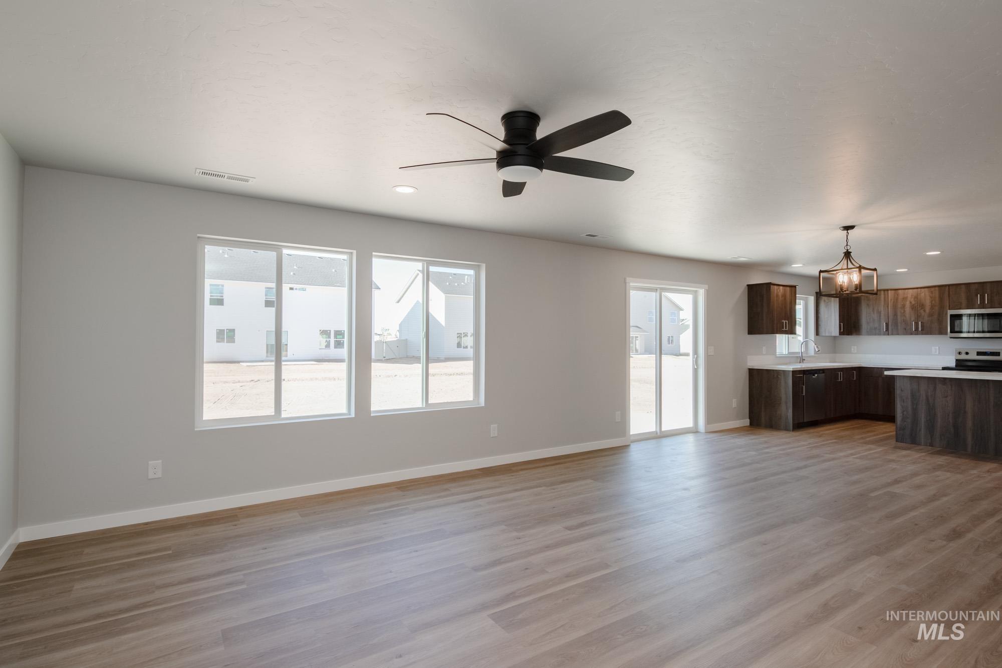 Unfurnished living room featuring light wood-style flooring, recessed lighting, a ceiling fan, and a chandelier