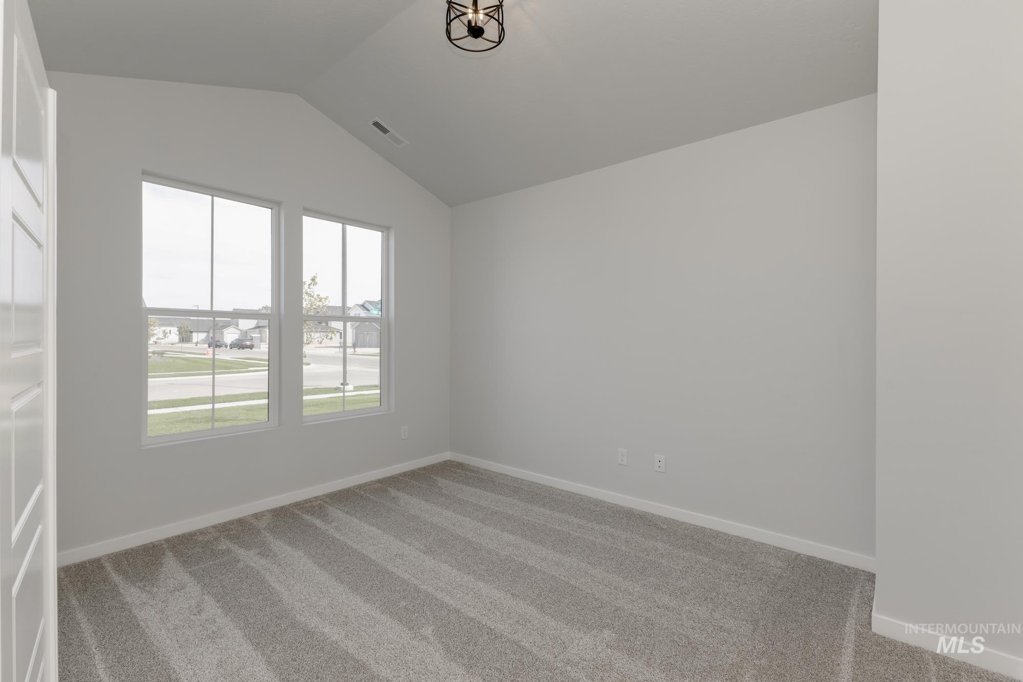 Carpeted empty room with baseboards and lofted ceiling