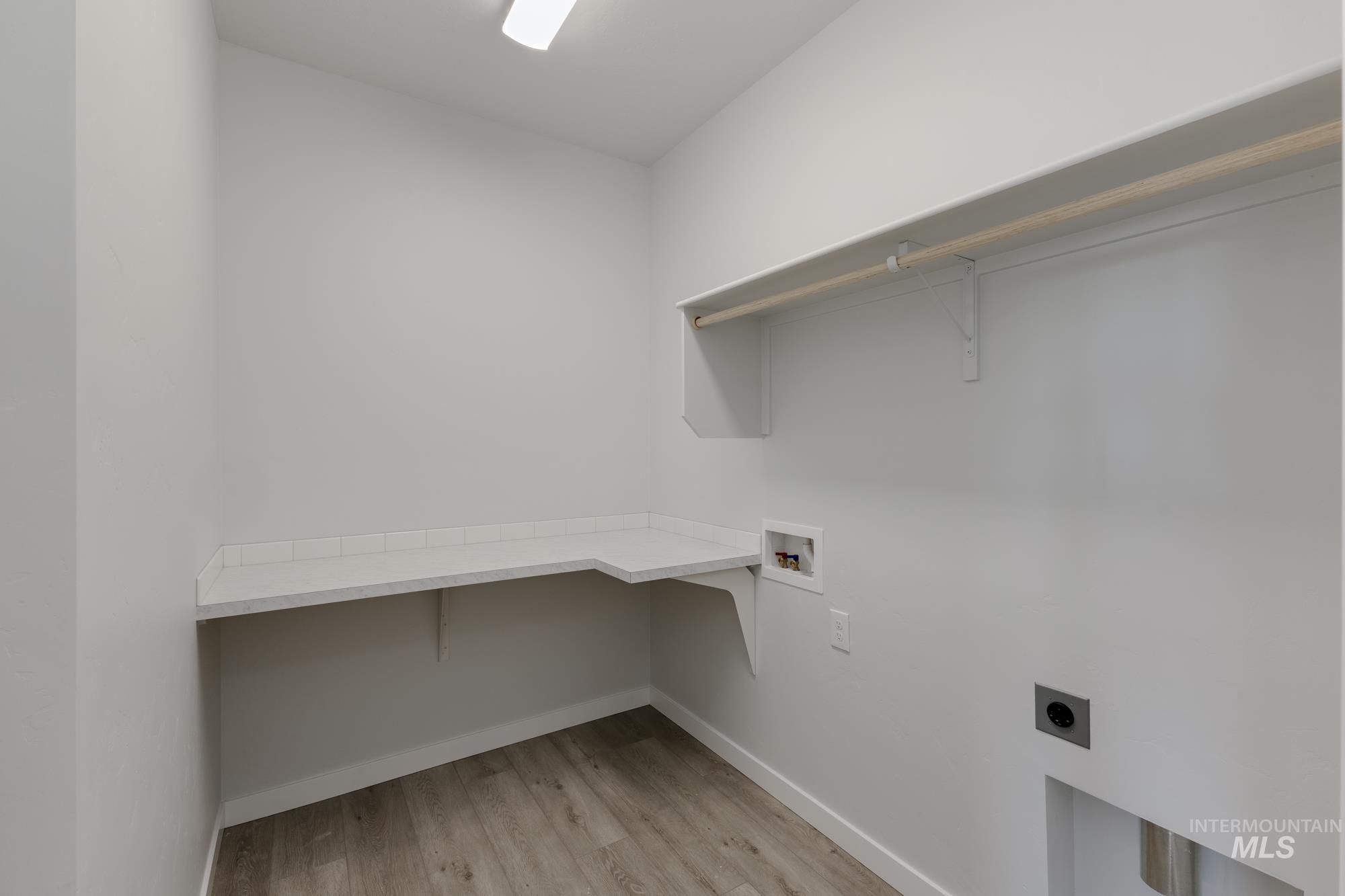 Washroom featuring light wood-style floors, hookup for a washing machine, electric dryer hookup, and an office area