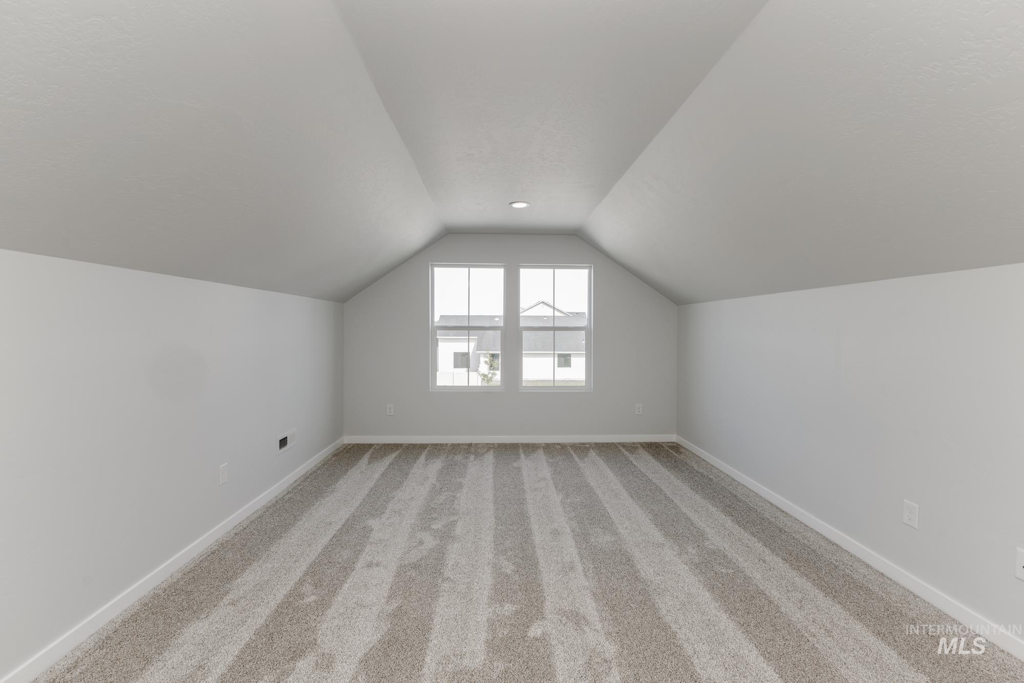 Additional living space featuring light carpet and lofted ceiling