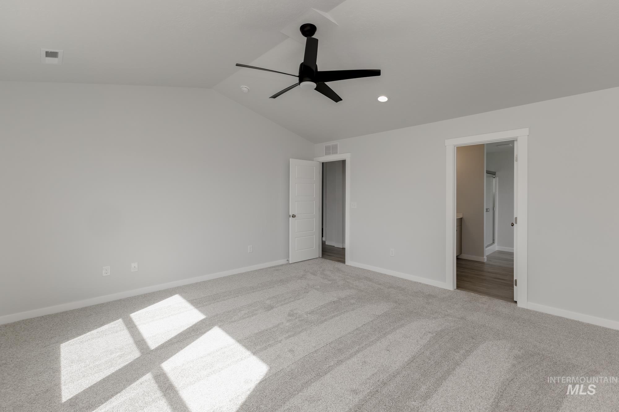 Unfurnished bedroom featuring lofted ceiling, a ceiling fan, light colored carpet, recessed lighting, and ensuite bathroom