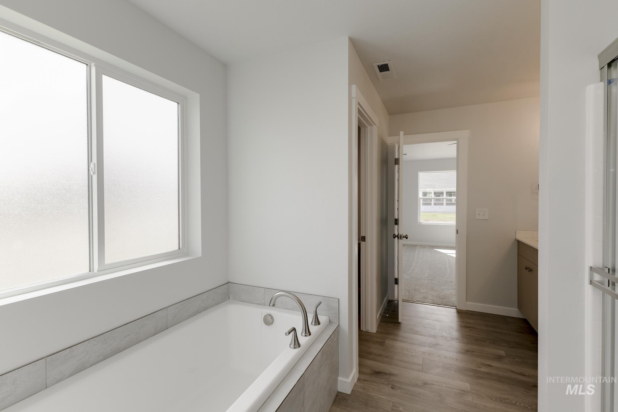 Full bathroom featuring a bath, vanity, and light wood-style flooring