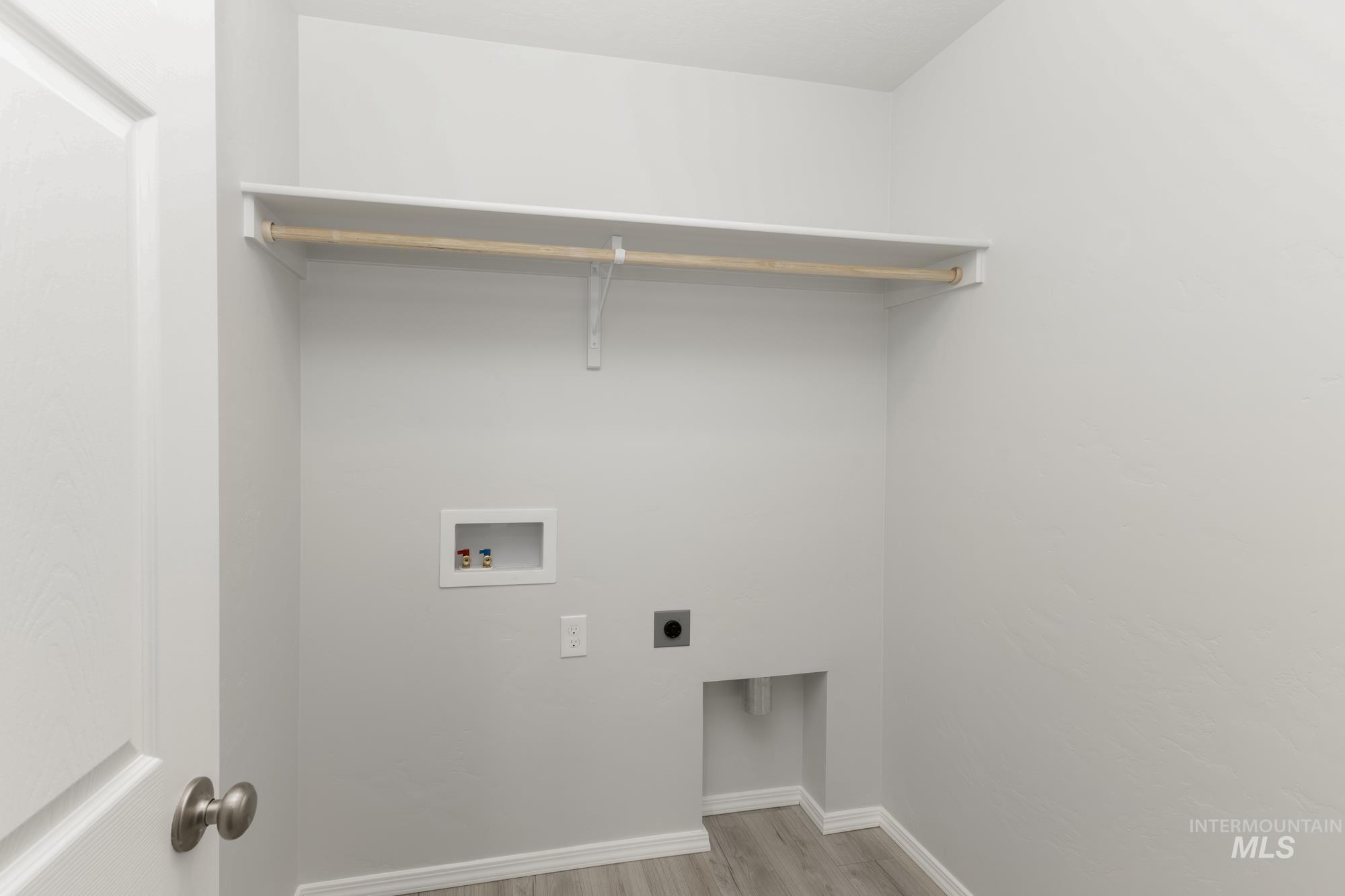 Laundry area with hookup for an electric dryer, light wood finished floors, and washer hookup