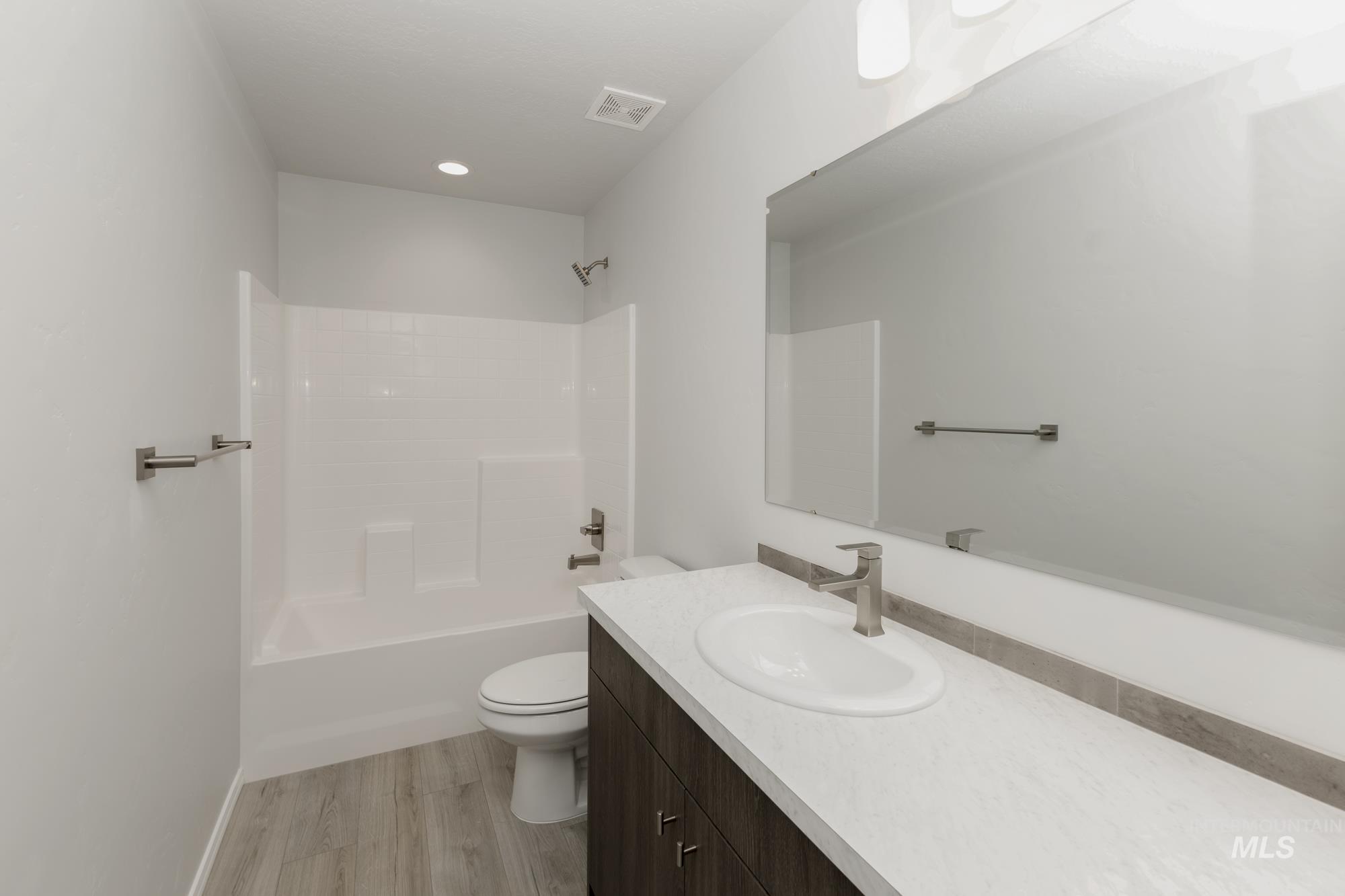 Full bathroom with vanity, shower / tub combination, and light wood-style flooring