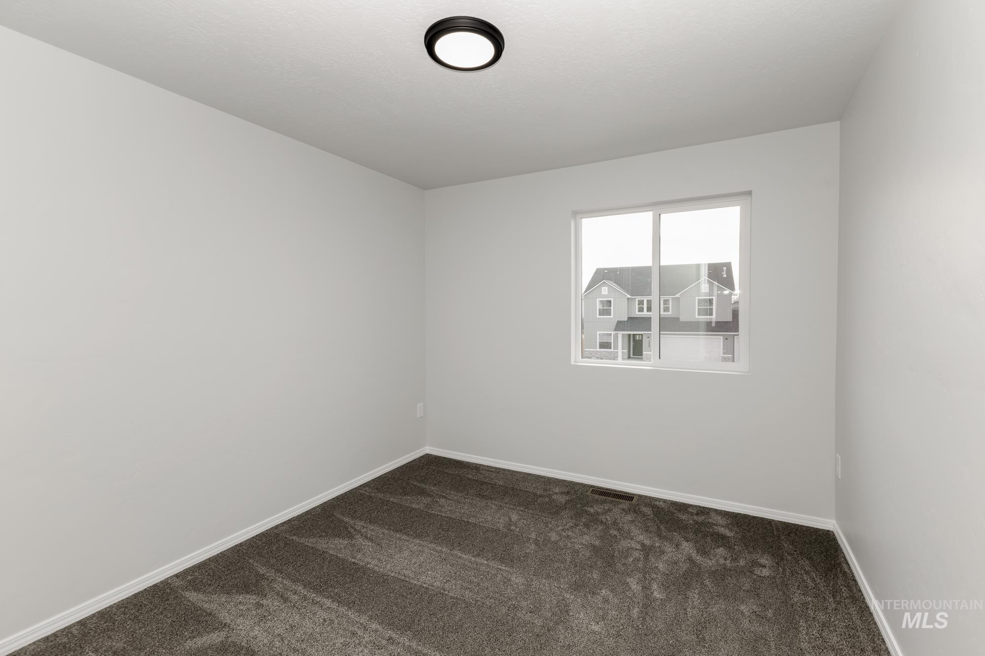 Empty room featuring dark colored carpet and baseboards