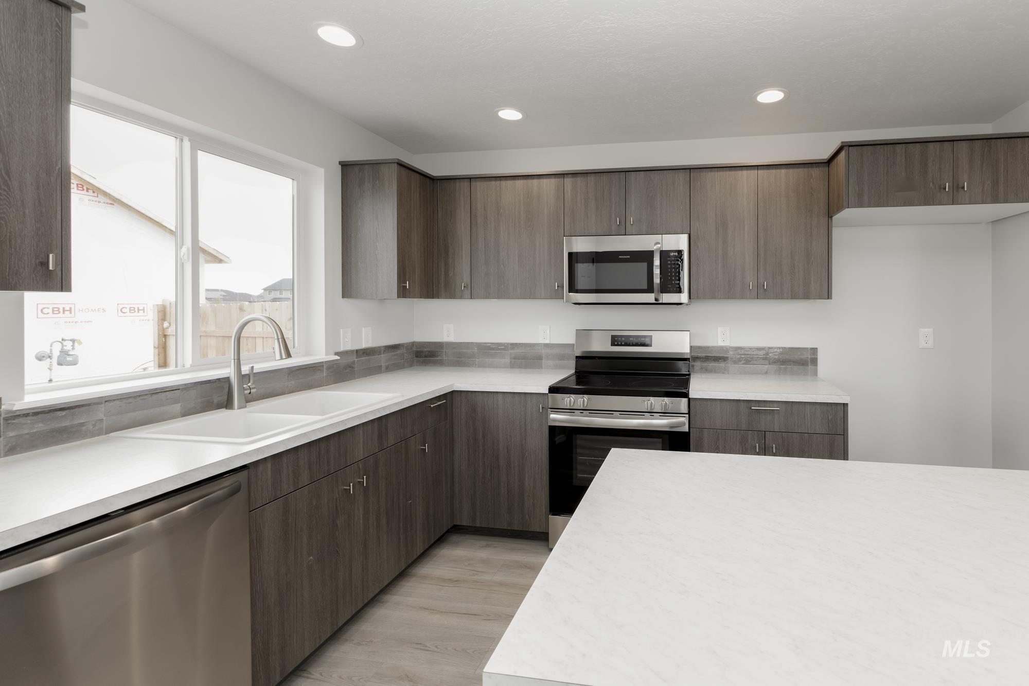 Kitchen with appliances with stainless steel finishes, light countertops, recessed lighting, light wood-style floors, and dark brown cabinetry