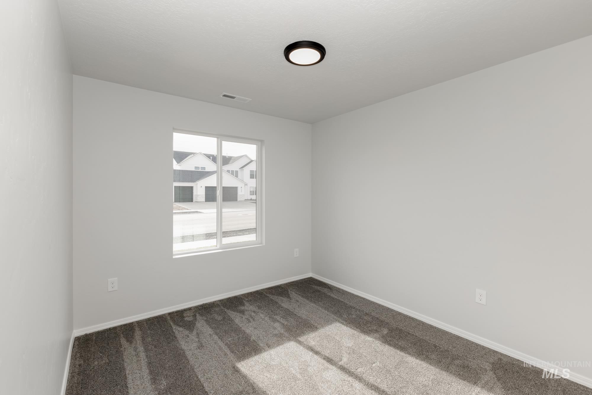 Spare room featuring carpet flooring and baseboards