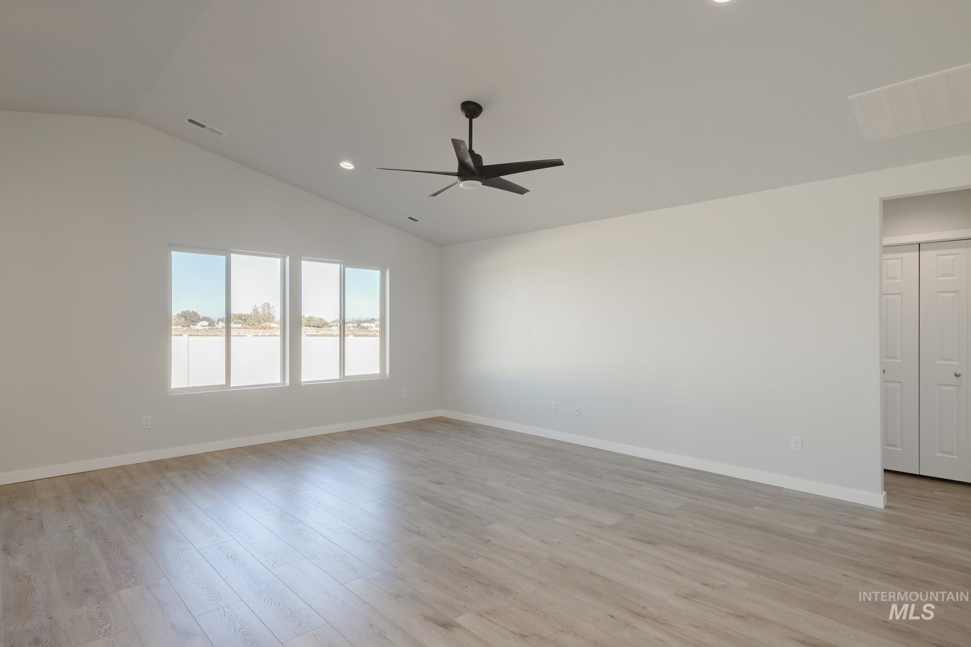 Empty room with light wood-style floors, recessed lighting, vaulted ceiling, and ceiling fan