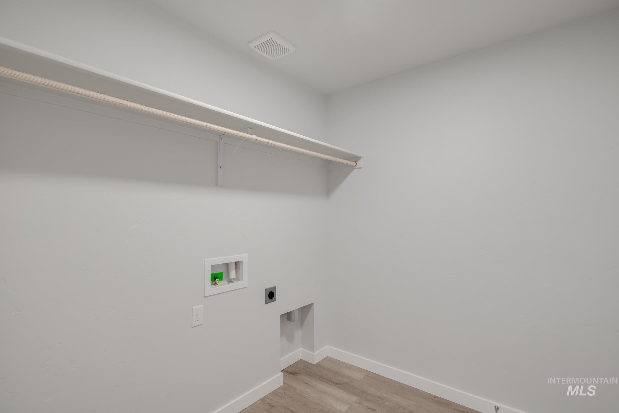 Washroom with light wood-style flooring, hookup for a washing machine, and electric dryer hookup