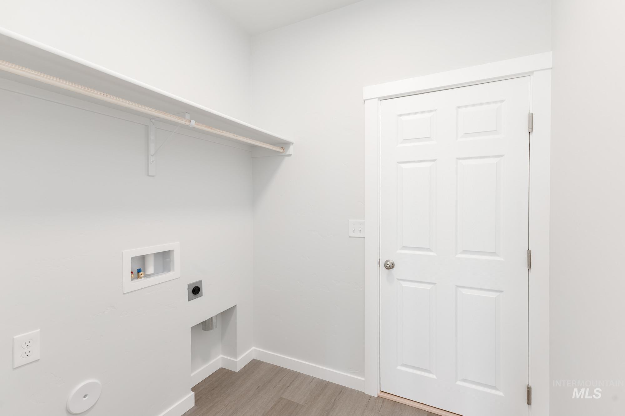 Laundry area with light wood-style flooring, washer hookup, and hookup for an electric dryer