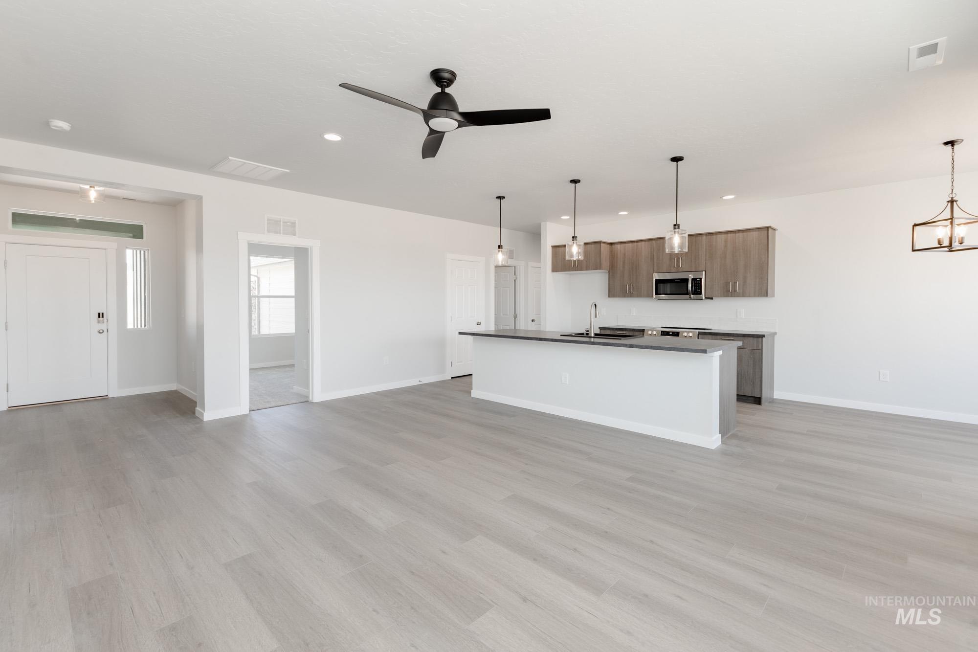 Kitchen featuring open floor plan, a kitchen island with sink, pendant lighting, ceiling fan, and recessed lighting