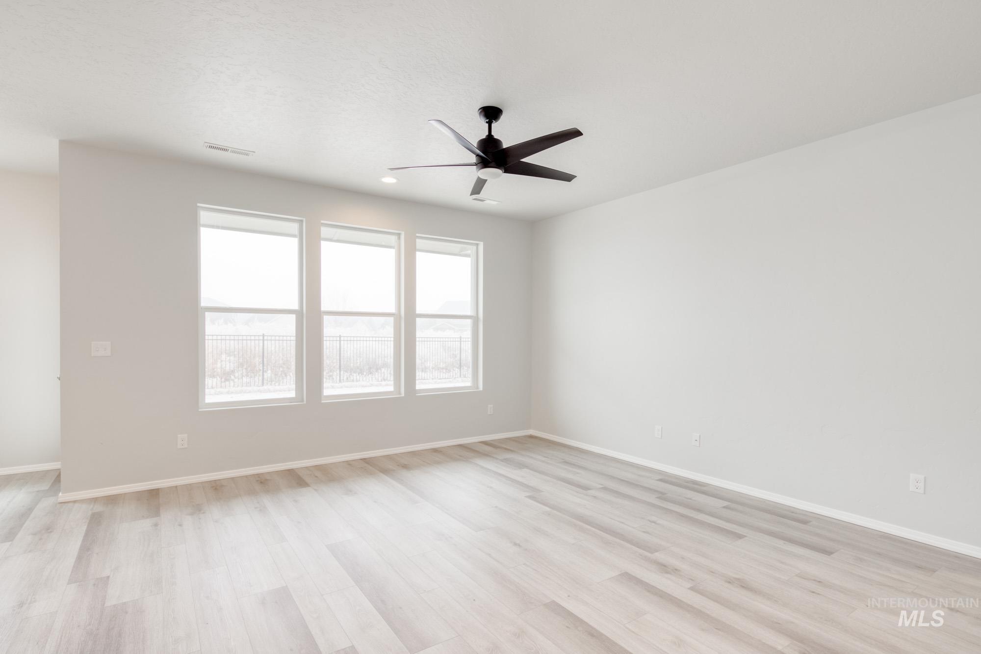 Empty room featuring light wood finished floors, ceiling fan, and recessed lighting