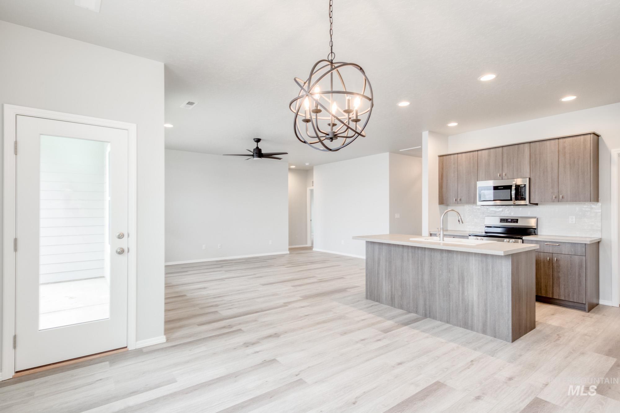 Kitchen featuring a kitchen island with sink, hanging light fixtures, open floor plan, ceiling fan, and appliances with stainless steel finishes