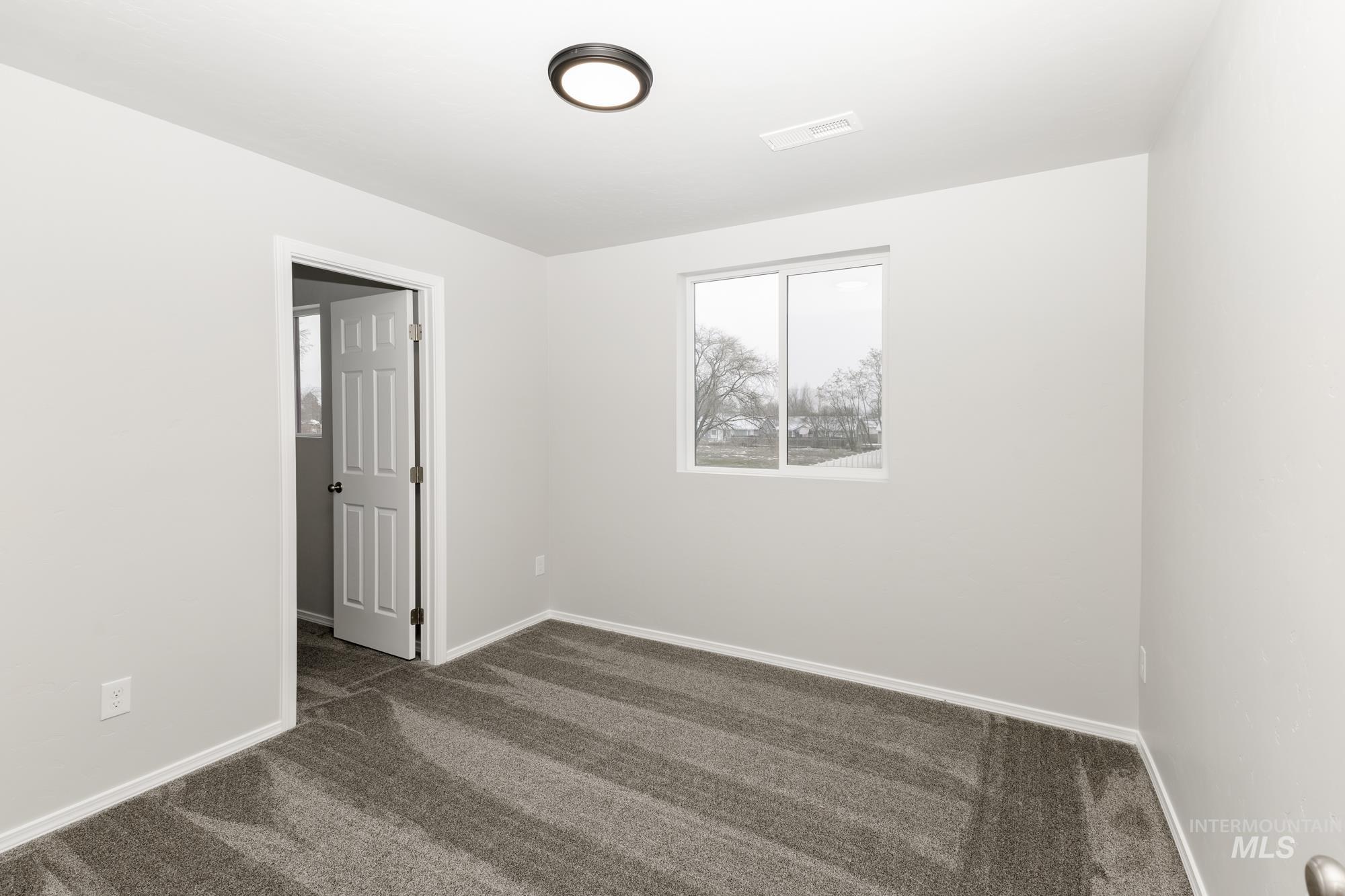 Empty room featuring dark carpet and baseboards