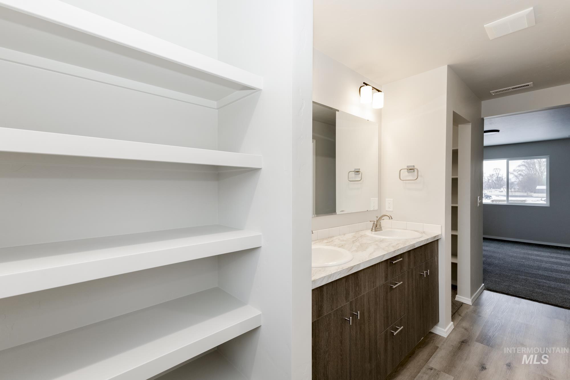 Bathroom with double vanity, light wood-type flooring, and built in features