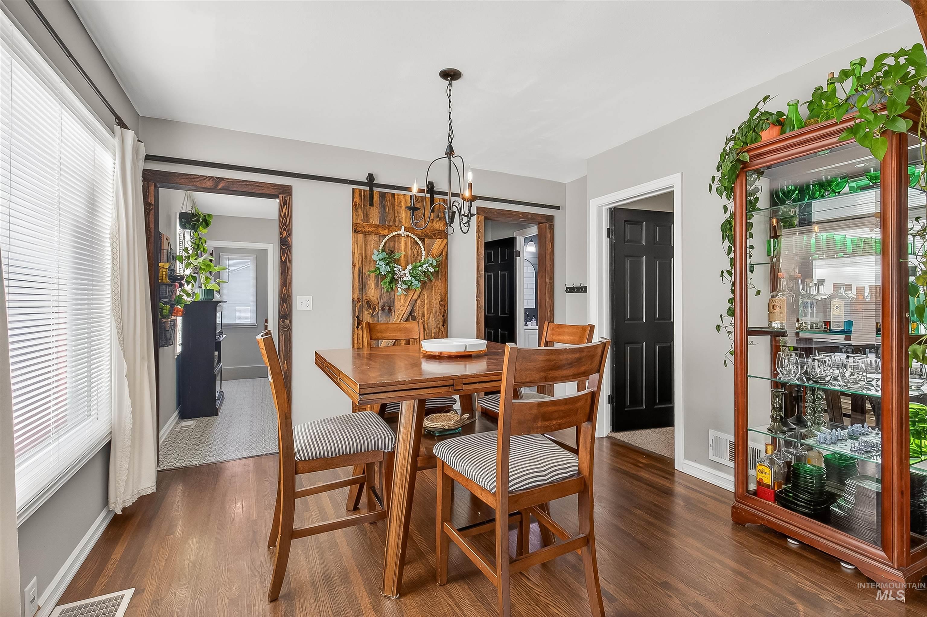 Dining space with a barn door and dark wood-style flooring