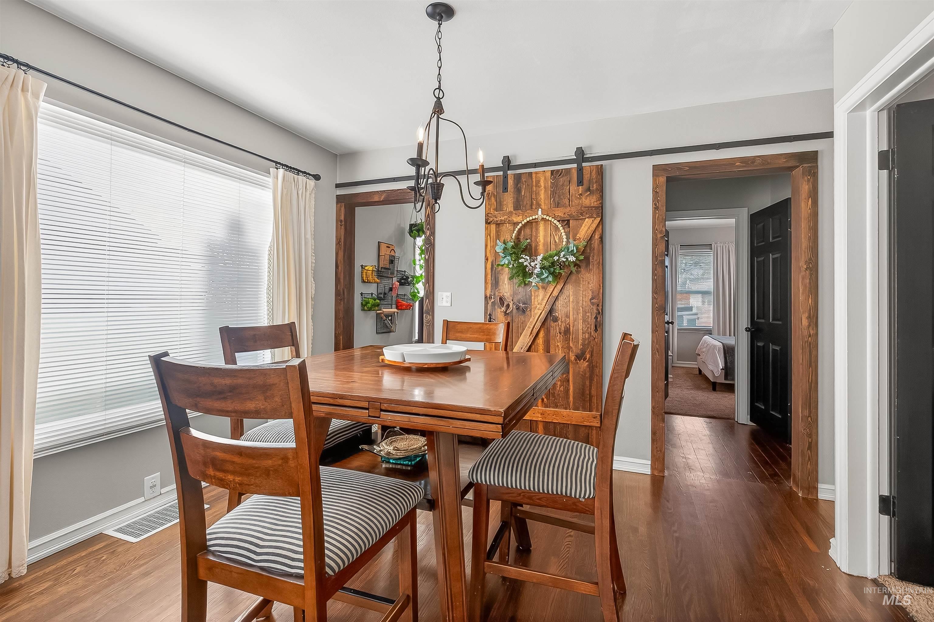 Dining room with a barn door, wood finished floors, plenty of natural light, and a chandelier