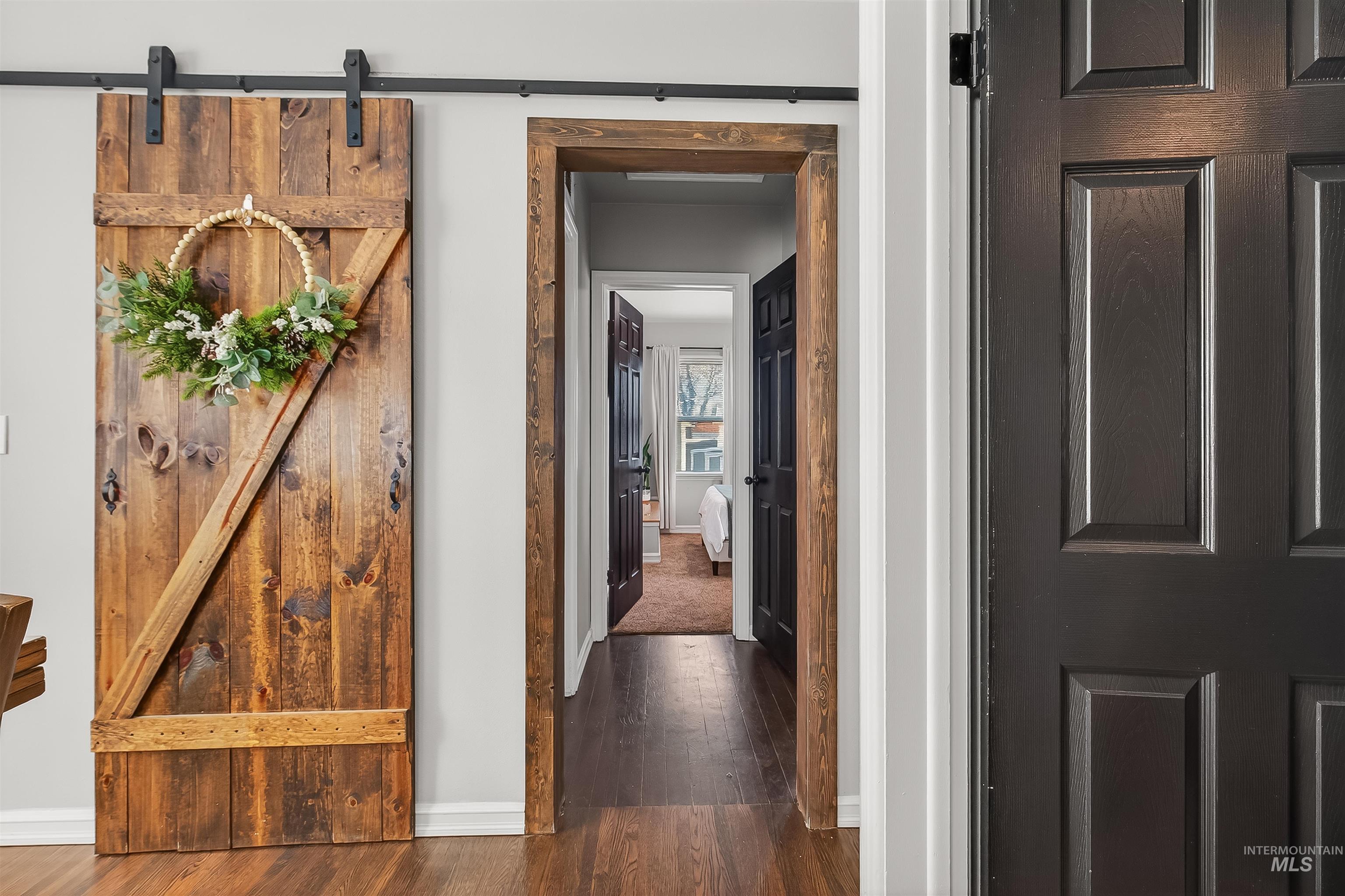 Hall featuring a barn door and dark wood-style floors