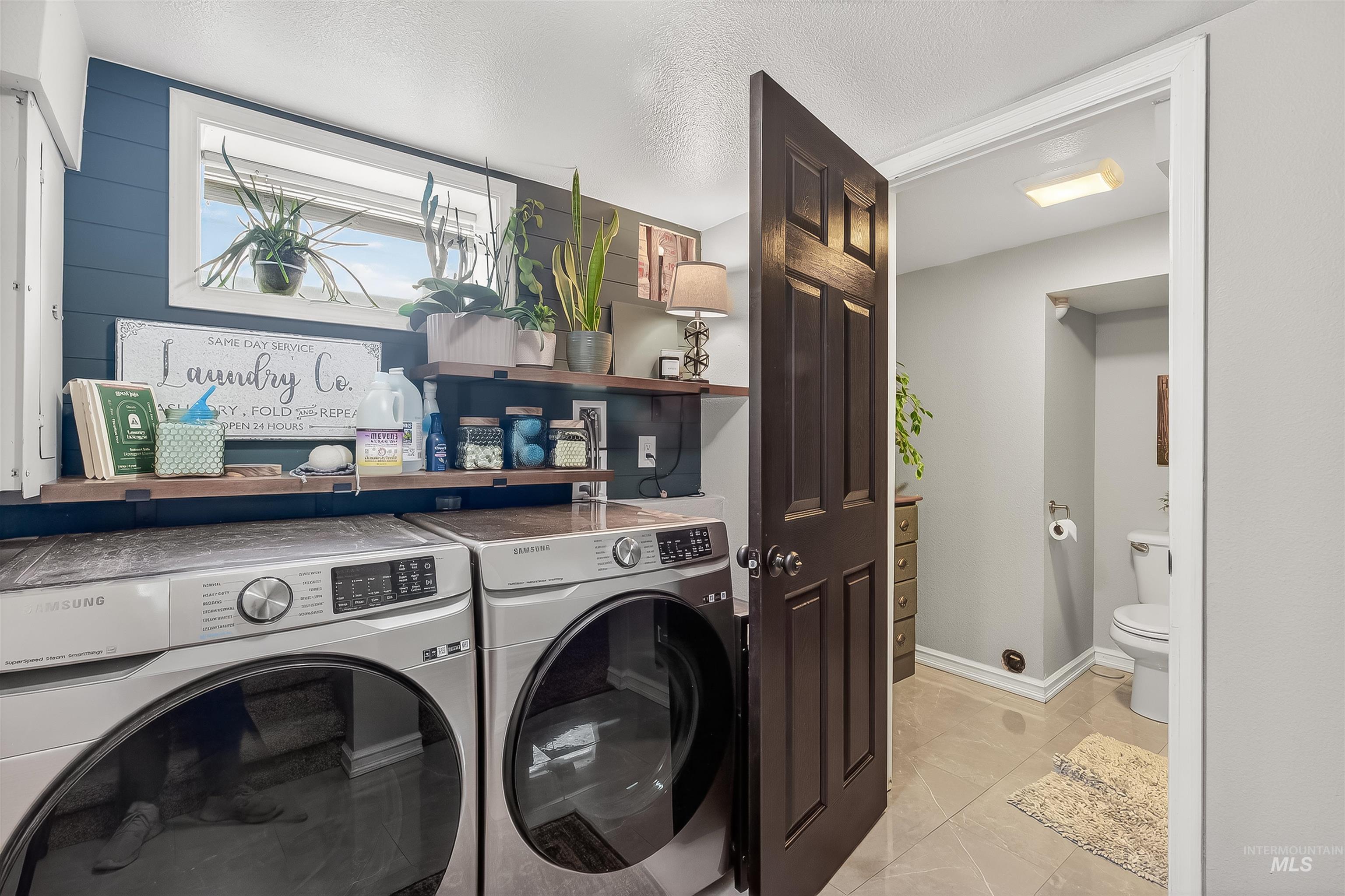 Laundry room featuring washing machine and clothes dryer, light tile patterned floors, and a textured ceiling