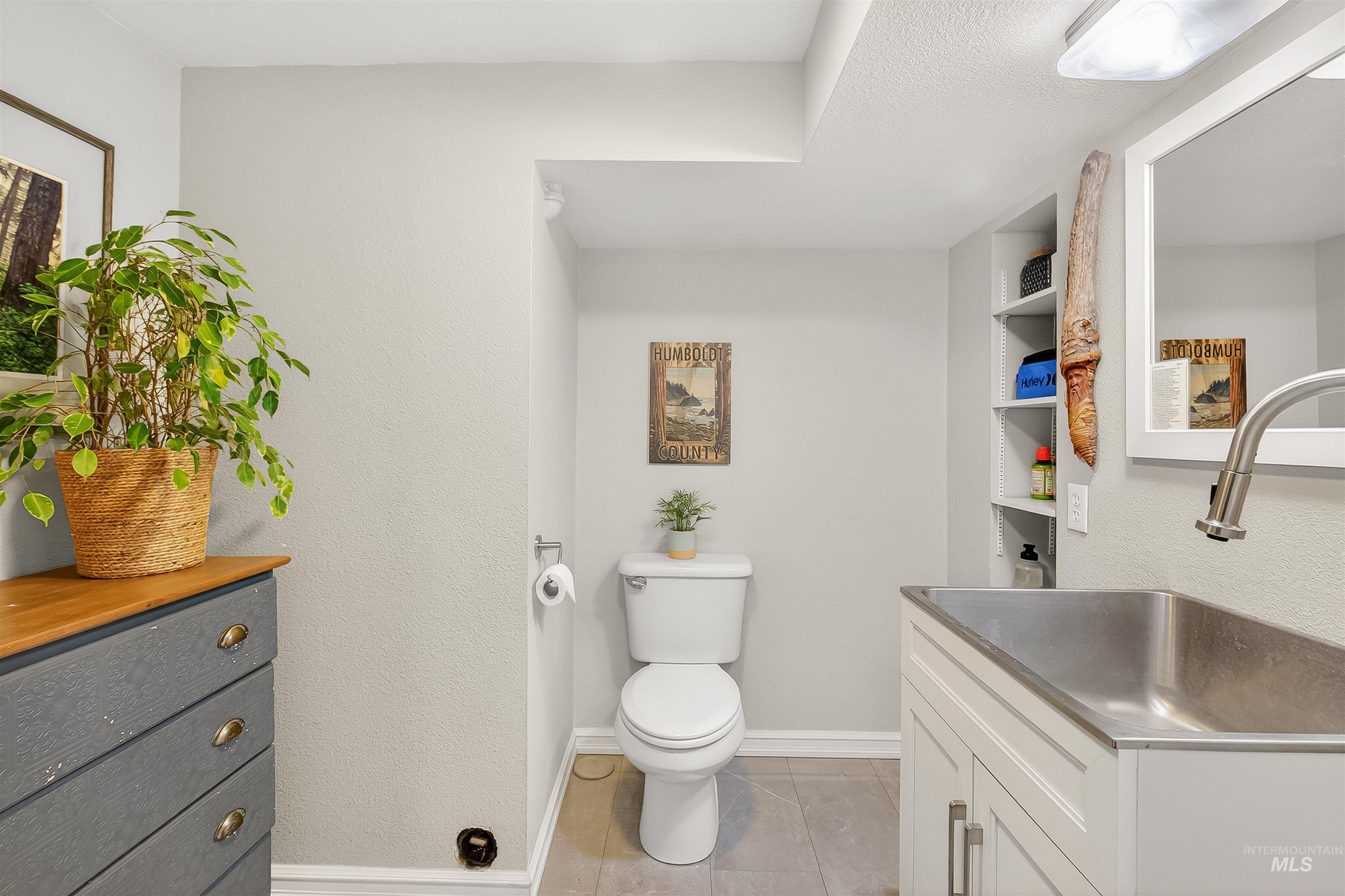Half bath featuring vanity, light tile patterned floors, and a textured wall