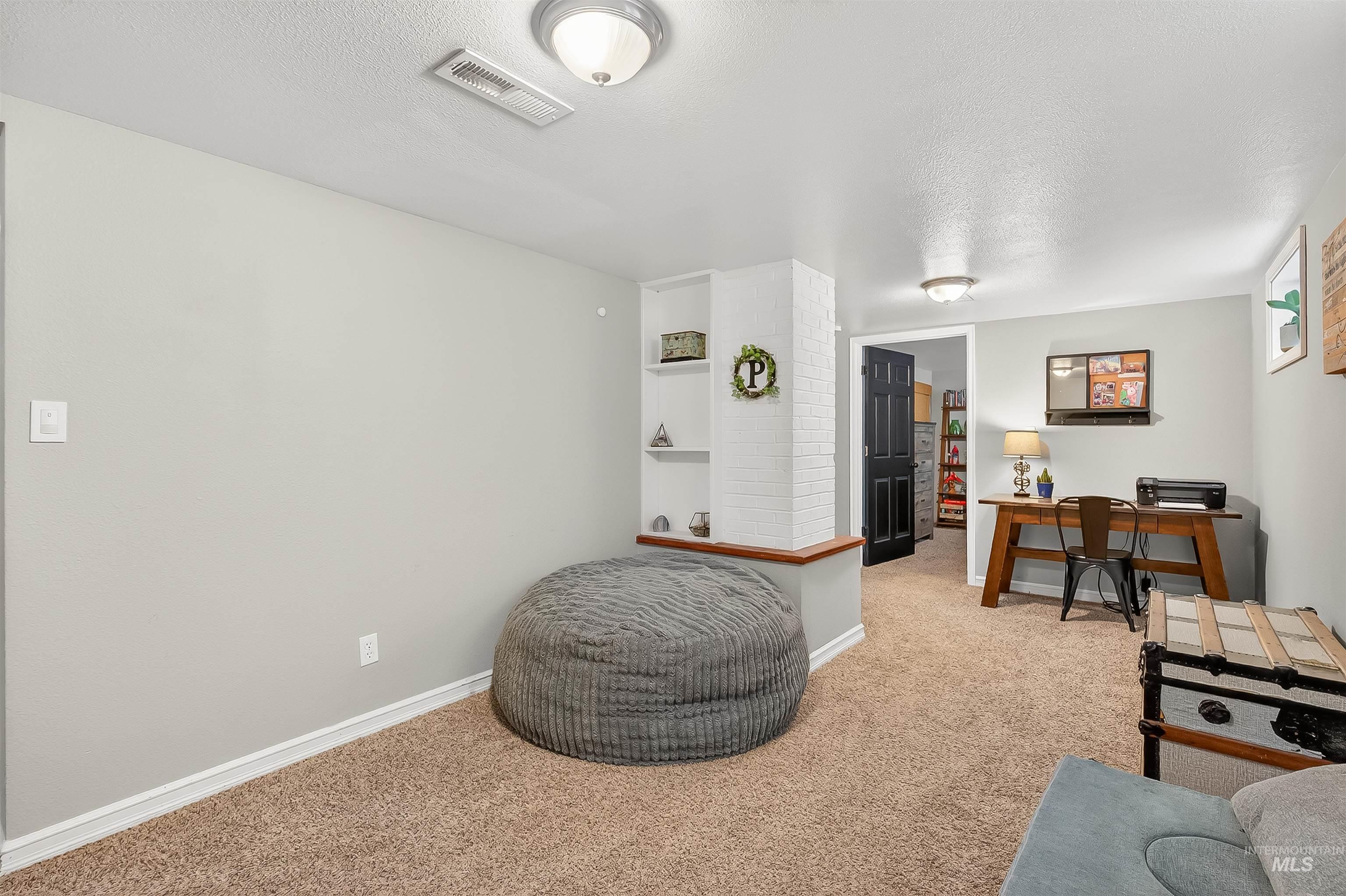 Living area featuring a textured ceiling, carpet, and a desk