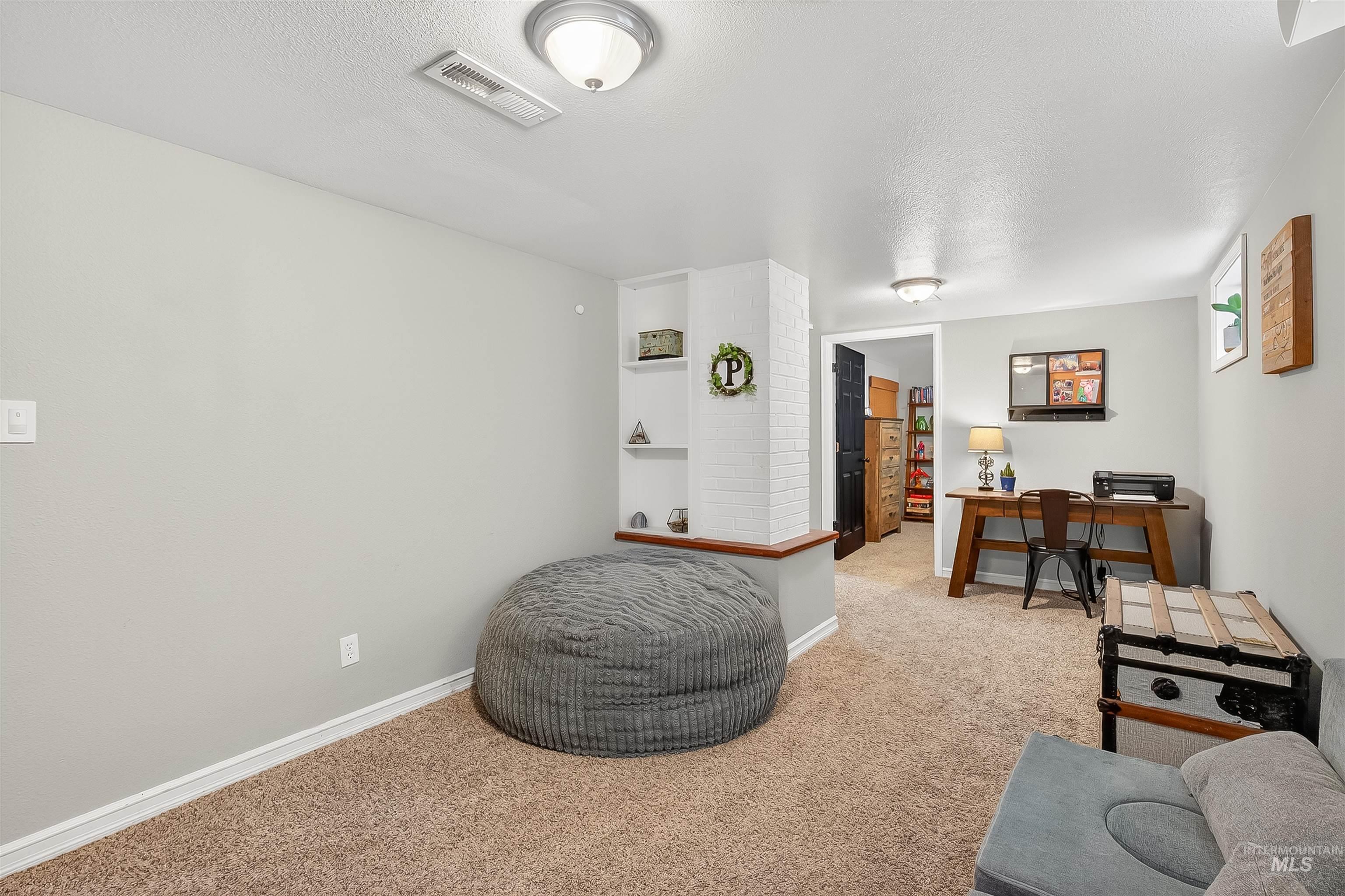 Sitting room featuring a textured ceiling, carpet floors, and a desk