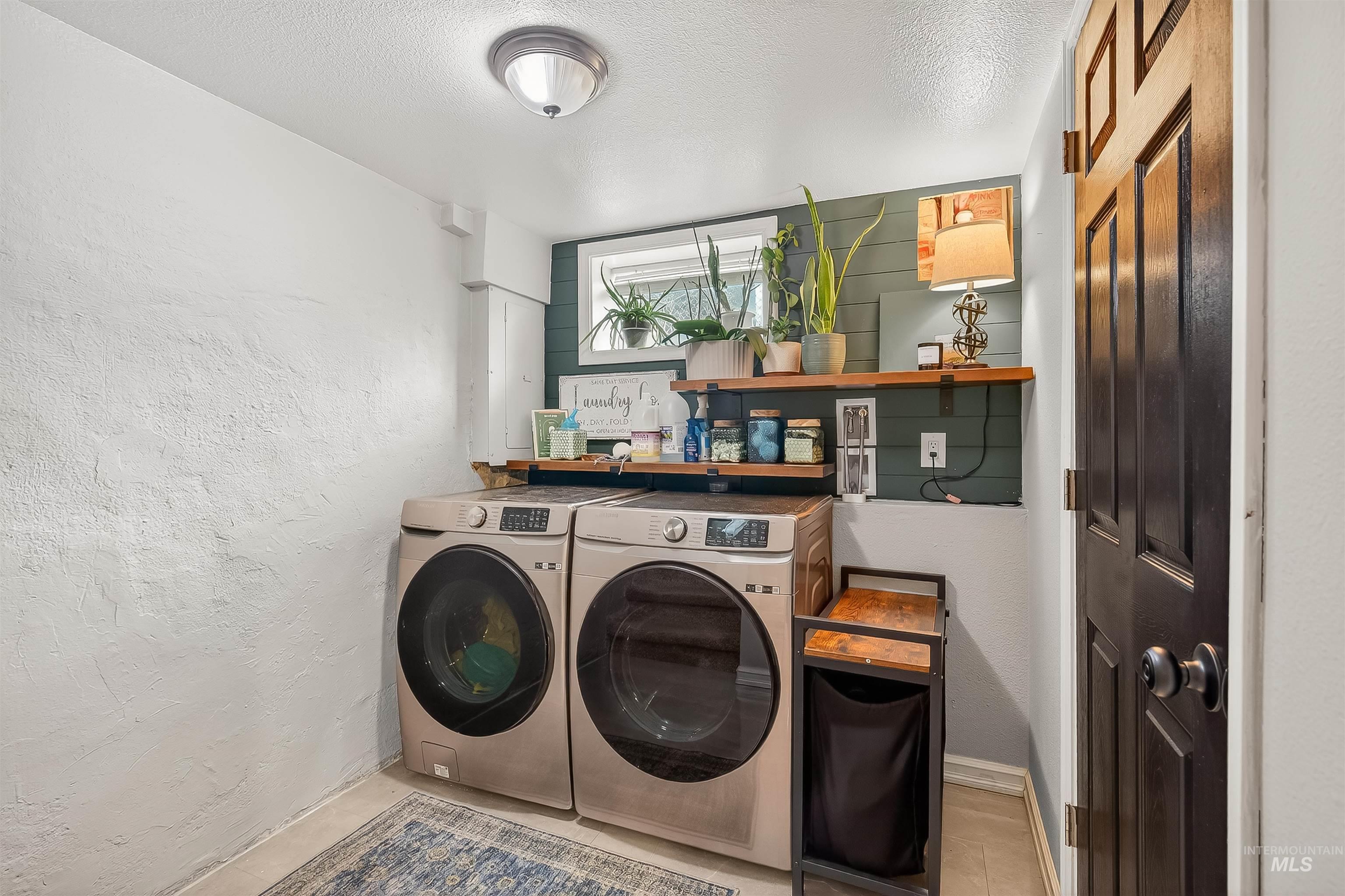 Laundry area featuring a textured wall, a textured ceiling, and washing machine and clothes dryer