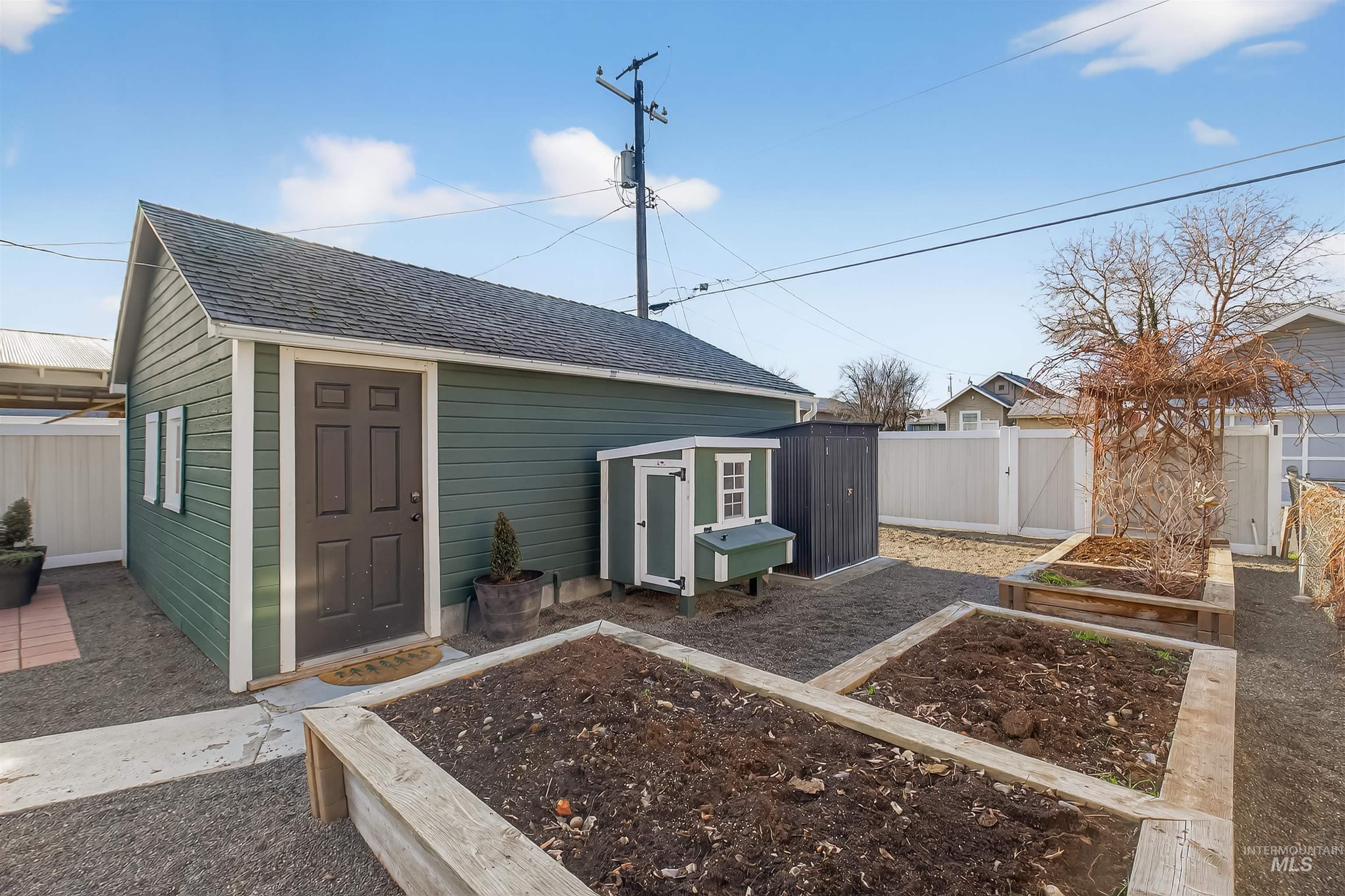 View of outdoor structure featuring a vegetable garden, a fenced backyard, and a gate