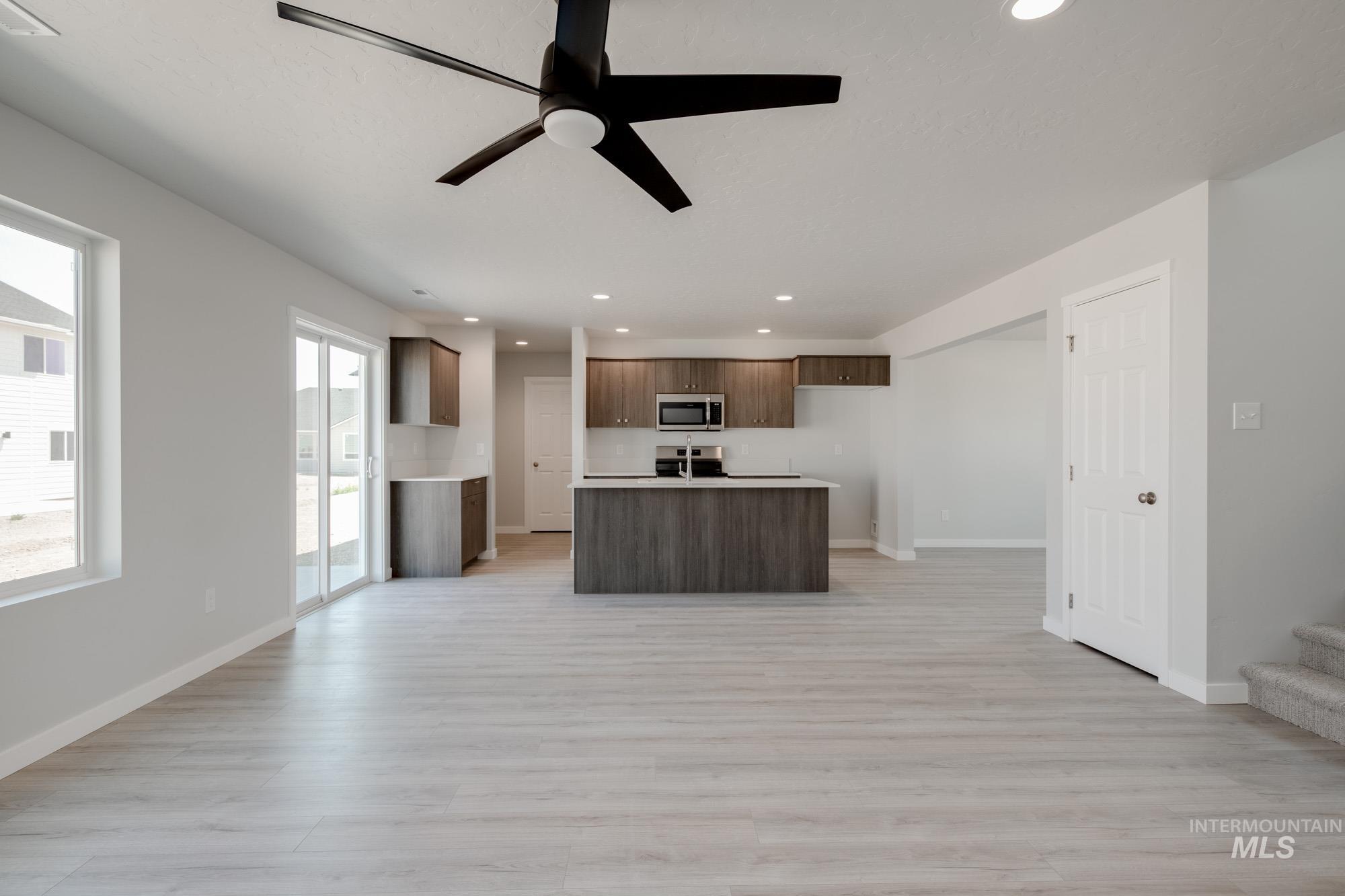 Kitchen with open floor plan, light countertops, recessed lighting, ceiling fan, and a kitchen island with sink