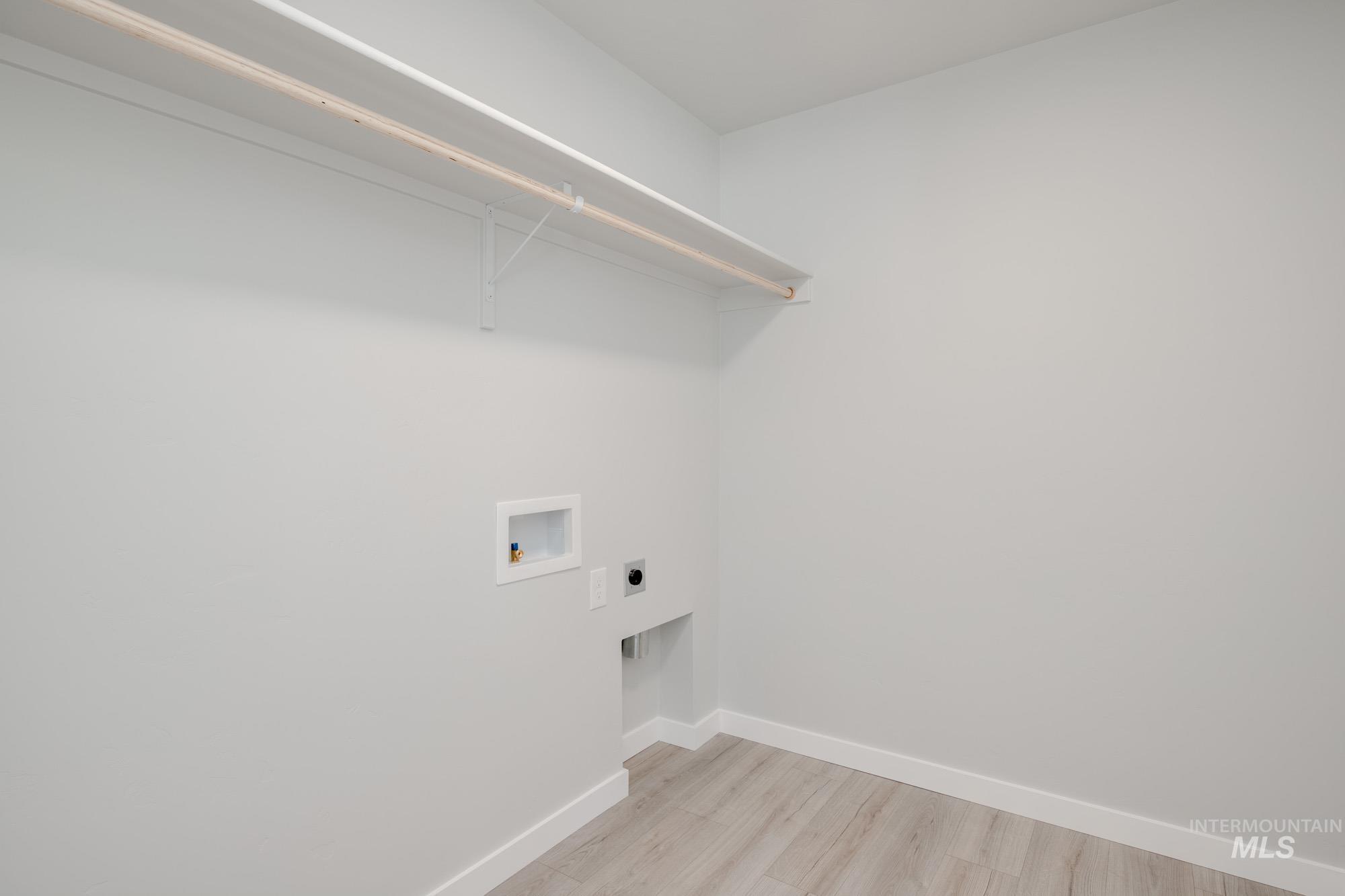 Washroom featuring hookup for a washing machine, light wood-style floors, and hookup for an electric dryer