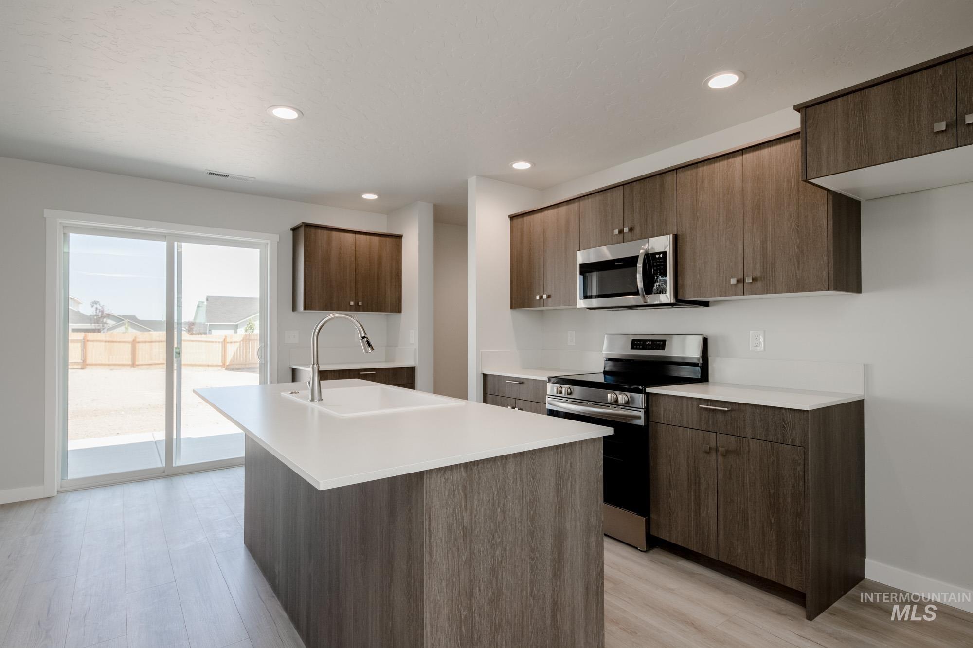 Kitchen featuring stainless steel appliances, modern cabinets, a kitchen island with sink, light wood-style flooring, and recessed lighting
