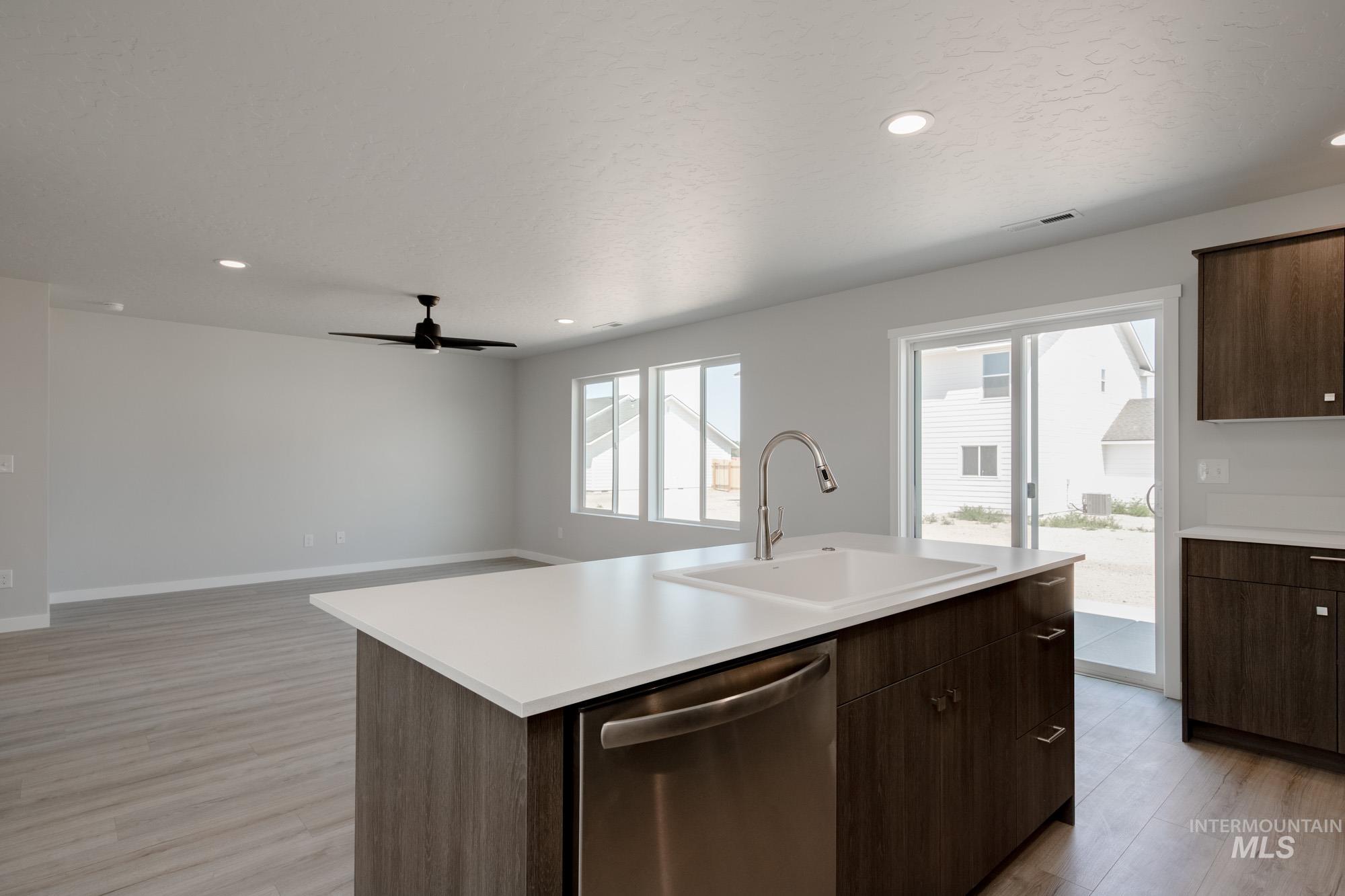 Kitchen featuring dark brown cabinetry, stainless steel dishwasher, light countertops, and recessed lighting