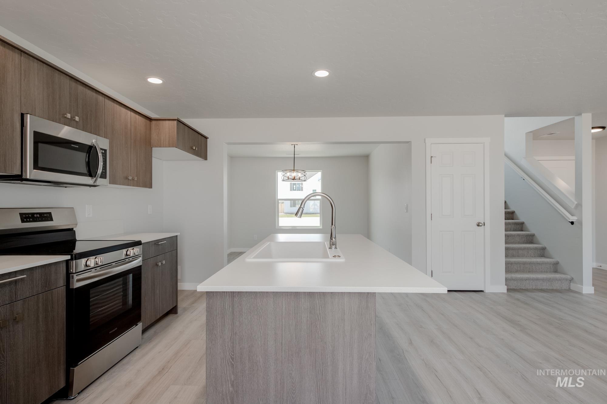 Kitchen featuring appliances with stainless steel finishes, modern cabinets, a kitchen island with sink, light wood finished floors, and pendant lighting
