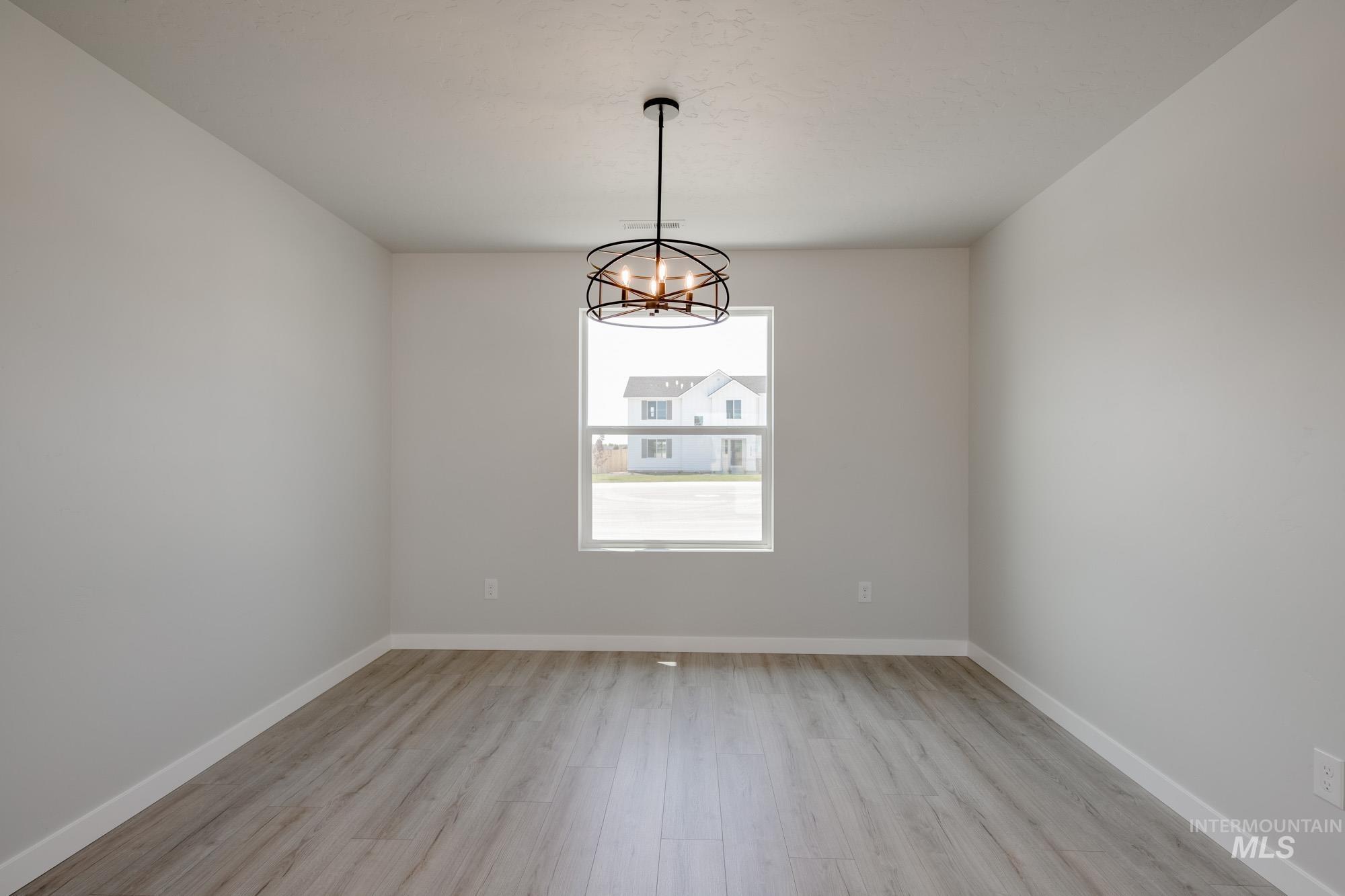 Empty room with light wood-style flooring and a chandelier