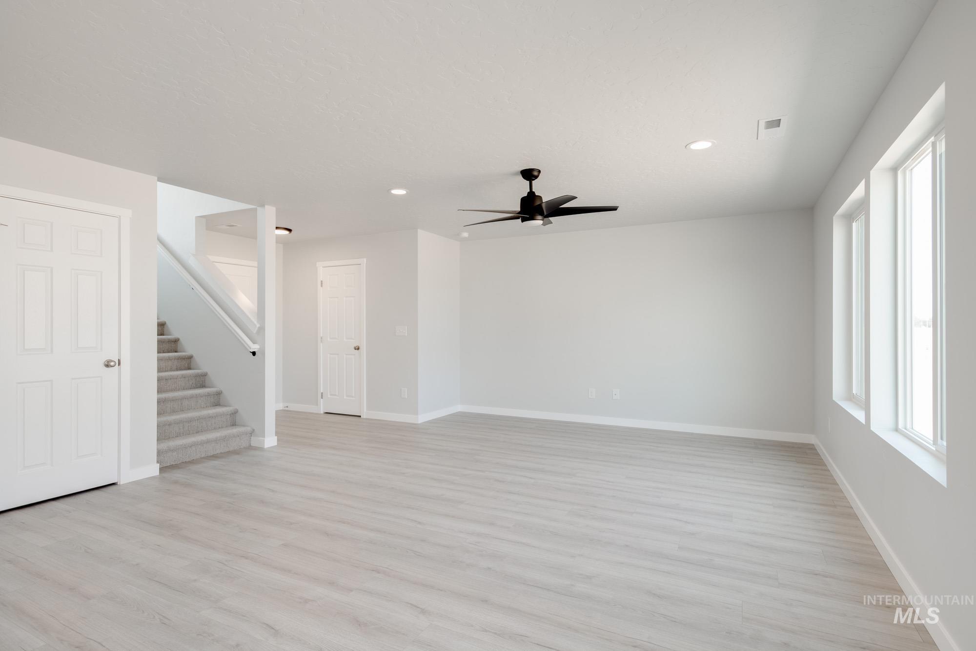 Unfurnished living room with stairs, light wood-style flooring, recessed lighting, and a ceiling fan