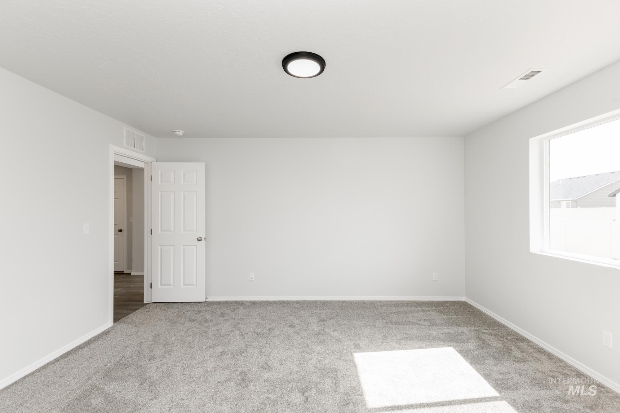 Spare room featuring carpet and baseboards