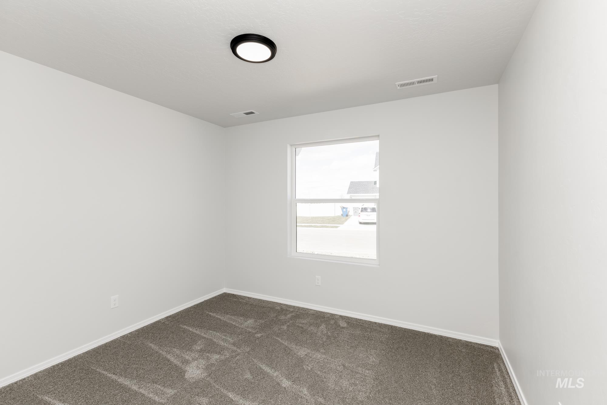 Spare room with dark carpet and baseboards