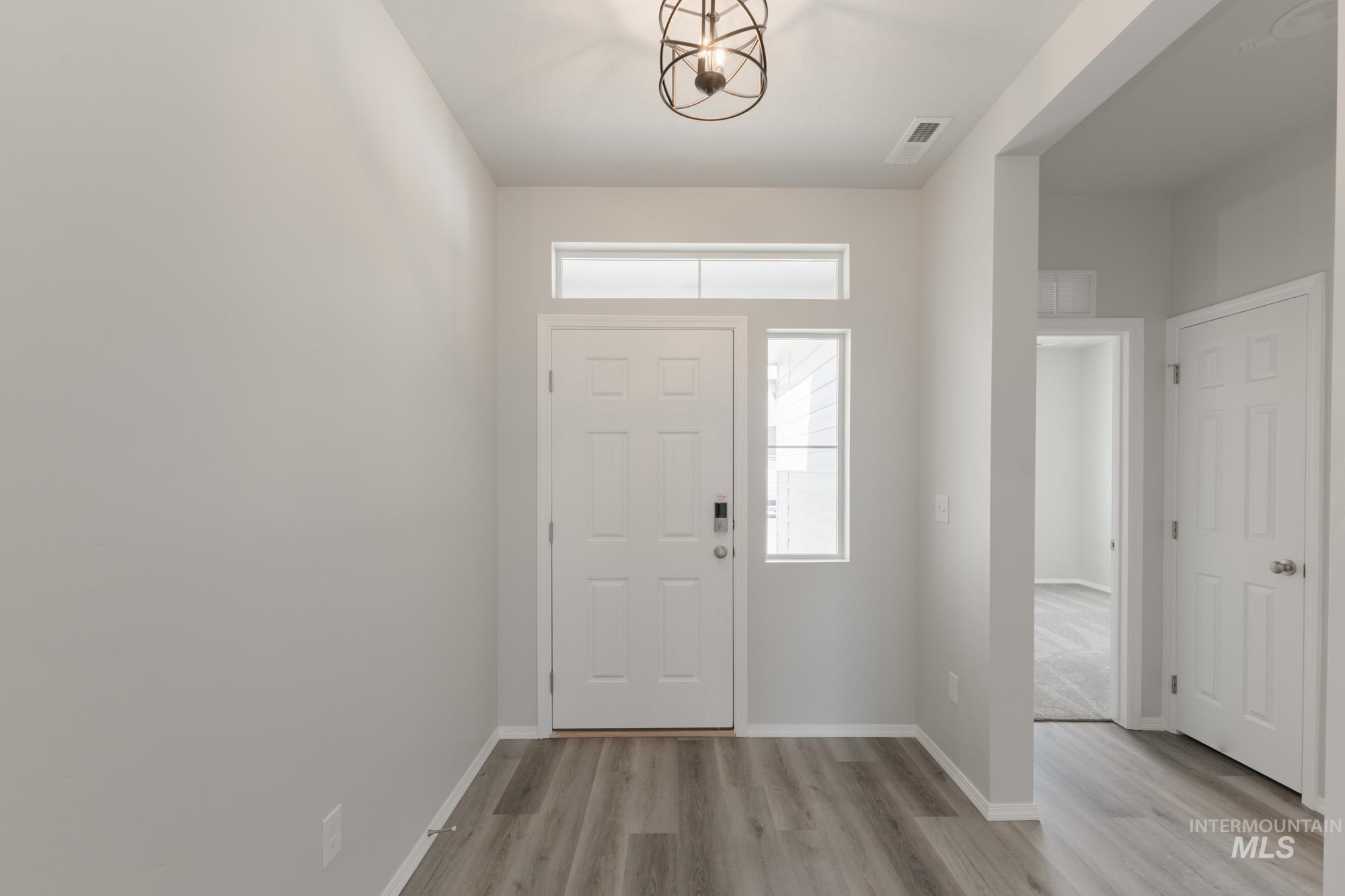 Foyer with light wood-type flooring and a chandelier