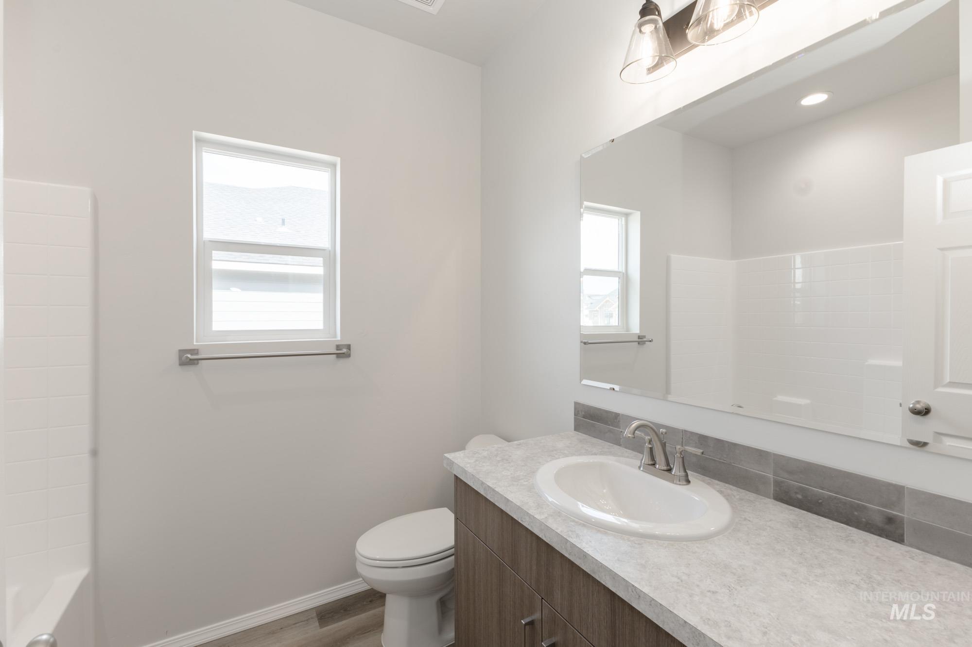 Full bath featuring vanity, light wood-style floors, and washtub / shower combination