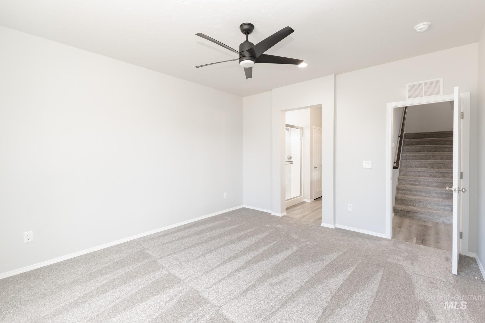 Unfurnished bedroom with a ceiling fan, ensuite bath, and light colored carpet