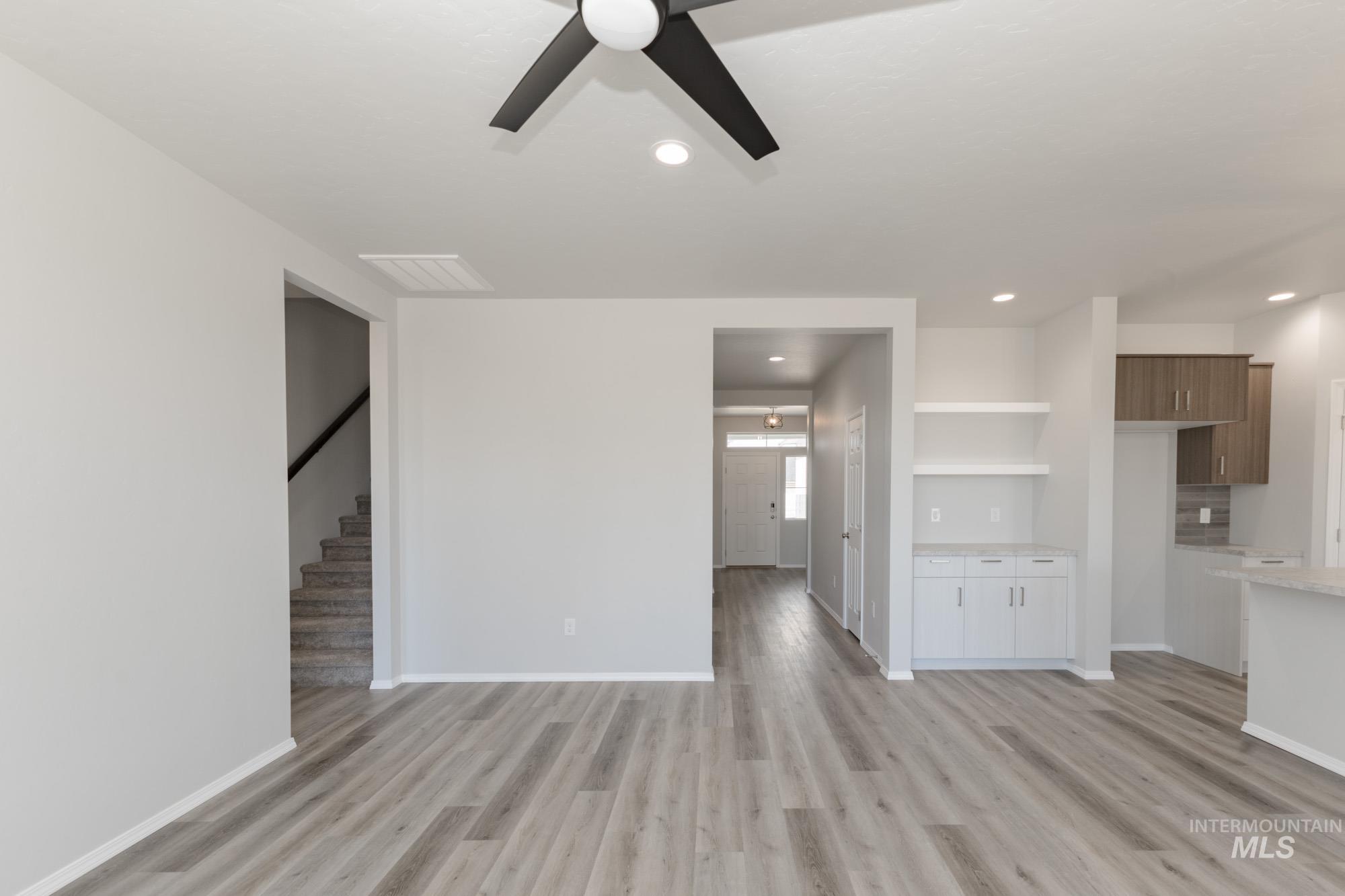 Unfurnished living room featuring light wood-type flooring, stairway, a ceiling fan, and recessed lighting